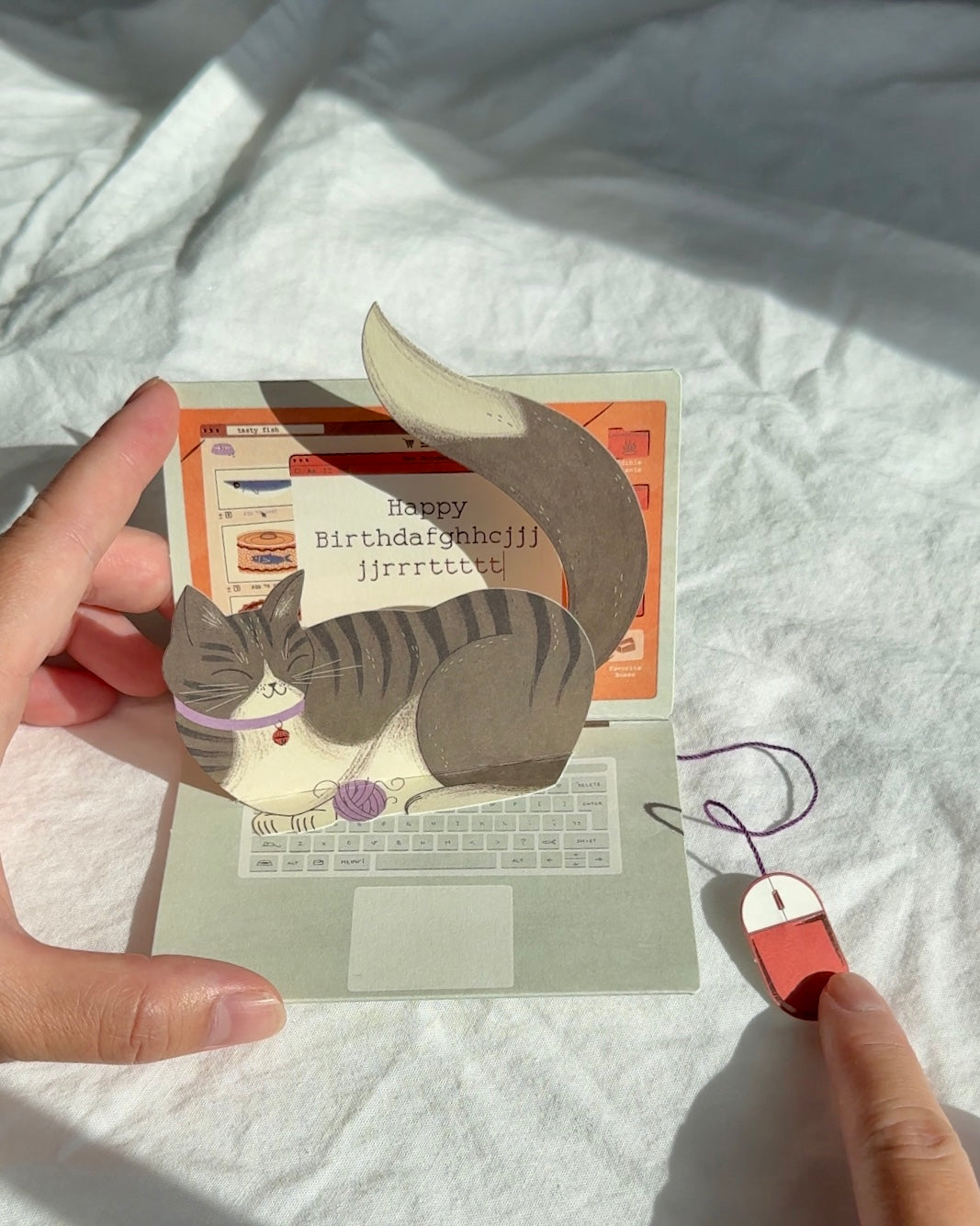 Interactive pop-up cat birthday card with red yarn mouse attached.