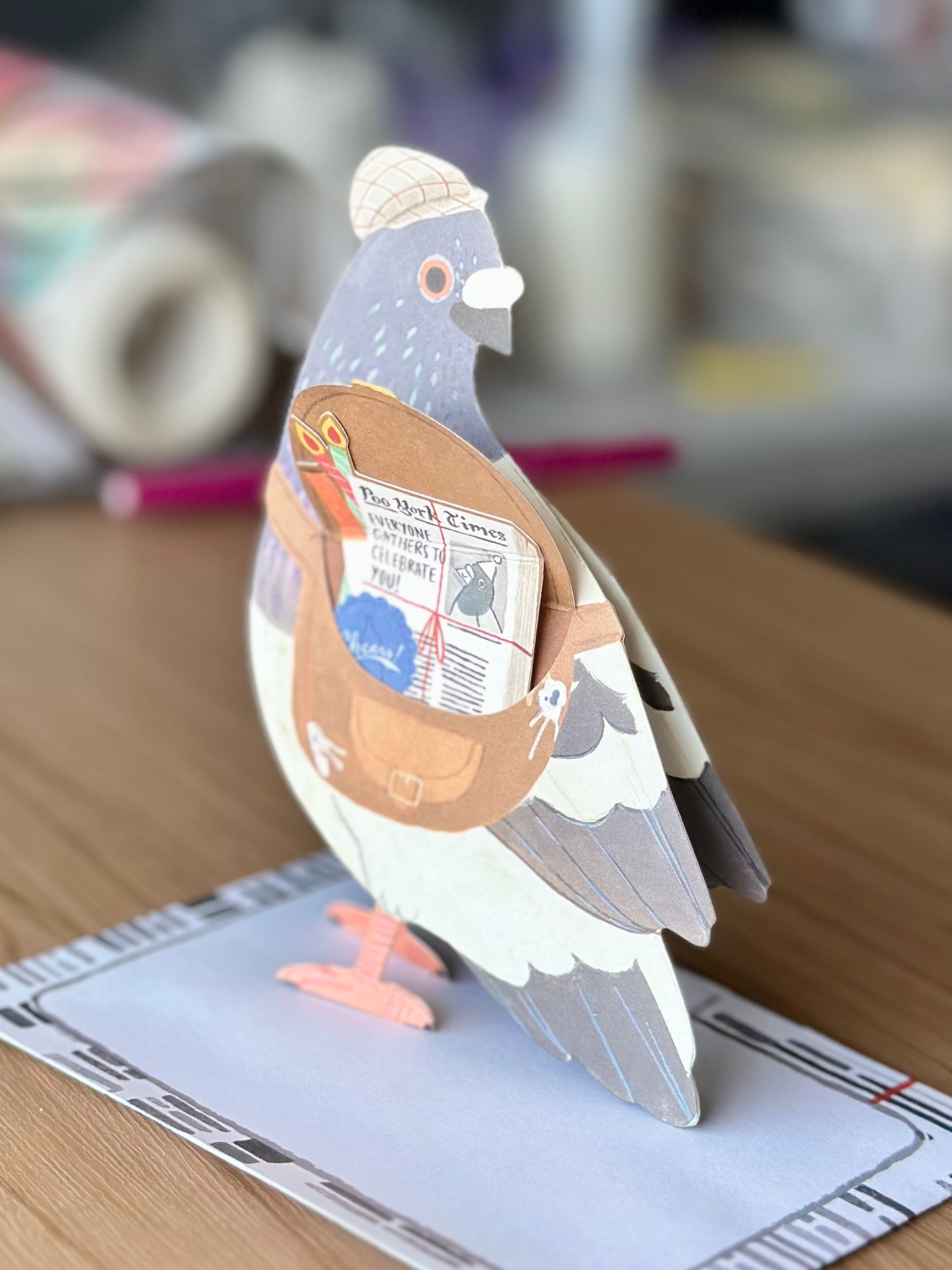 Side profile of pigeon pop-up greeting card showing “Poo York Times” newspaper surprise.