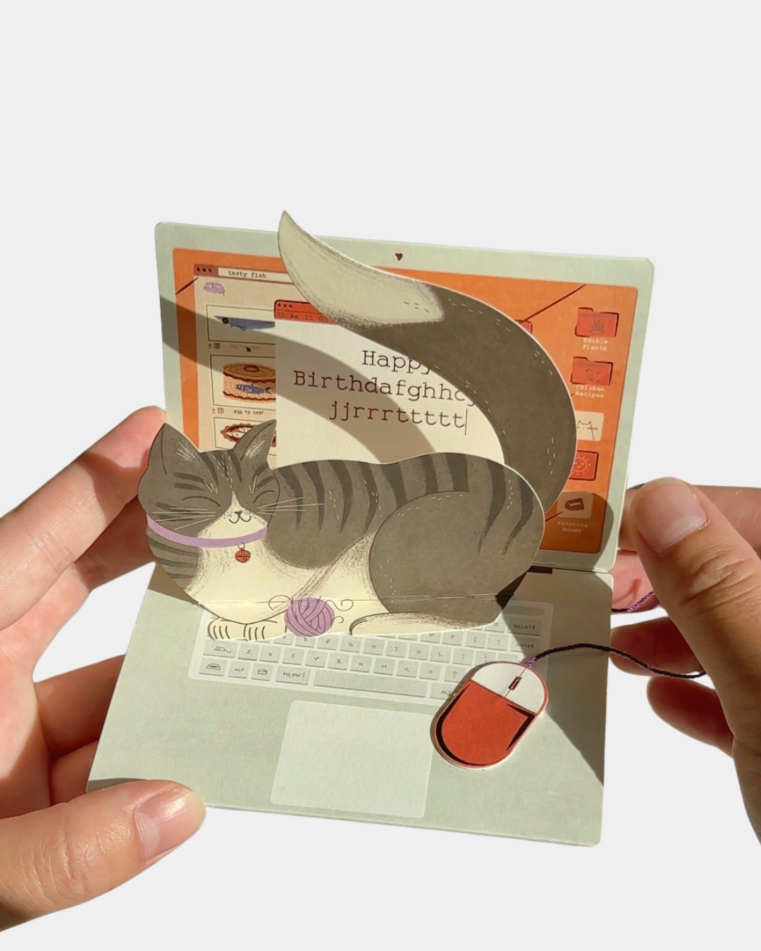 Funny pop-up cat birthday card with mischievous kitty typing on laptop keyboard.