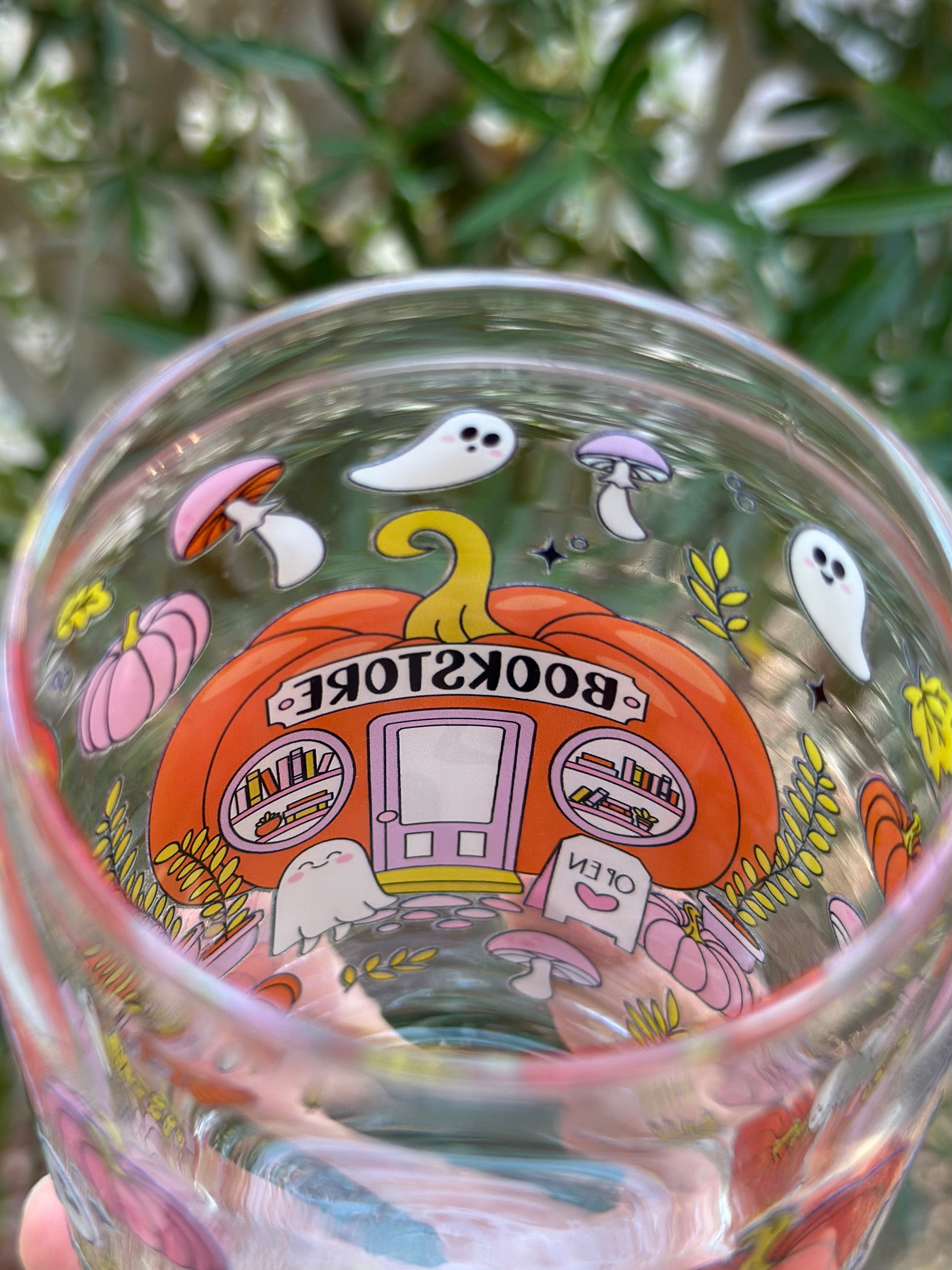 Inside top view of pumpkin bookstore glass can cup with bookshelves, a ghost, and colorful autumn decorations.
