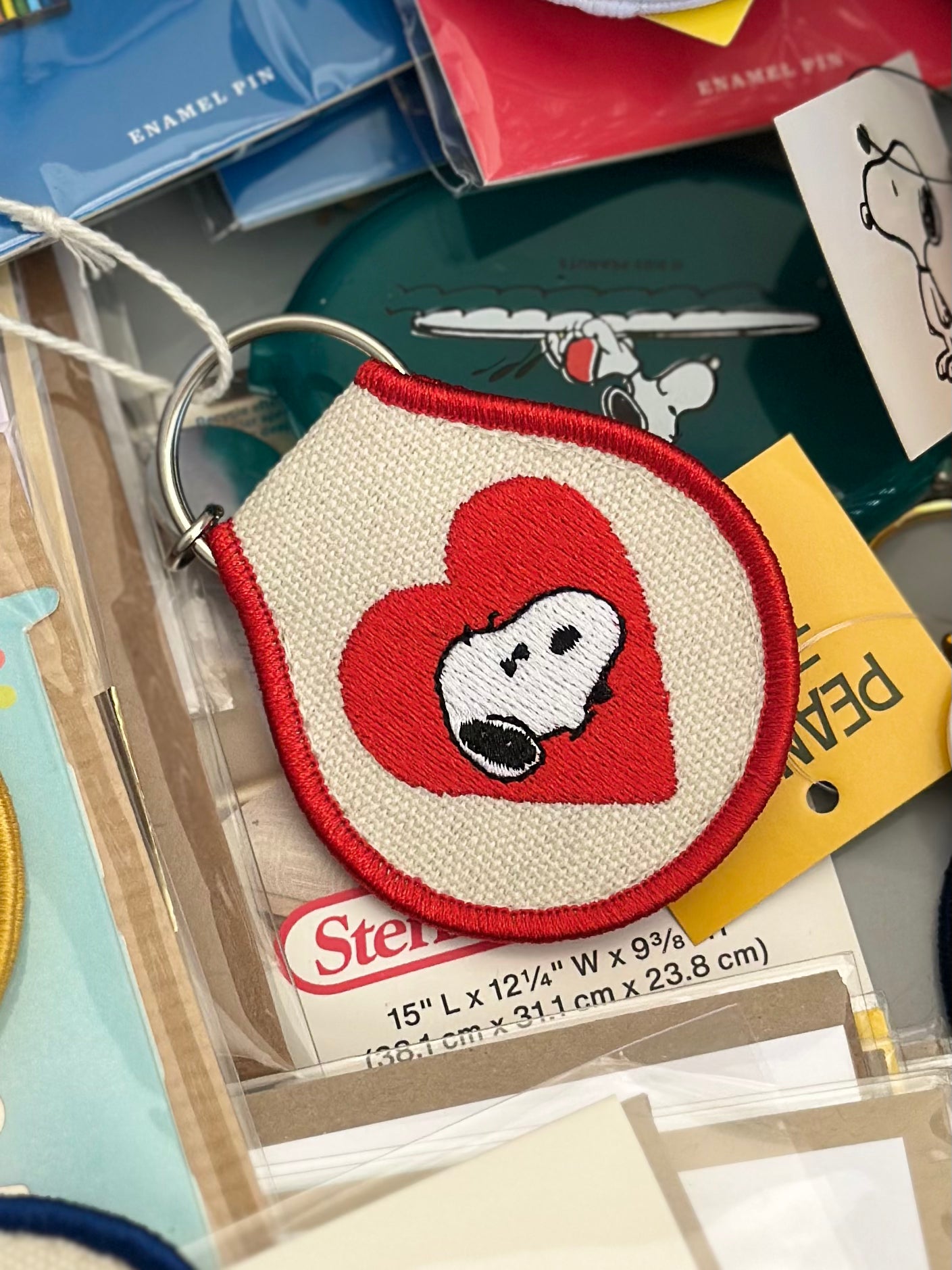 Embroidered Snoopy heart keychain featuring his face inside a red heart on cream canvas with red trim.