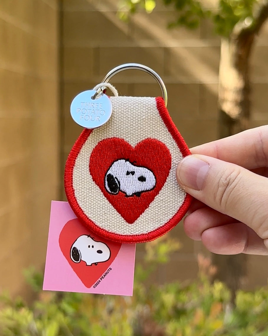 Snoopy Heart keychain with red heart and Snoopy design, shown hanging by metal ring with Peanuts tag.