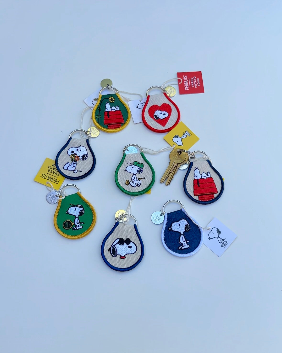 Collection of Snoopy Peanuts embroidered keychains in assorted designs, including golf, tennis, sunglasses Snoopy, and Snoopy on doghouse.