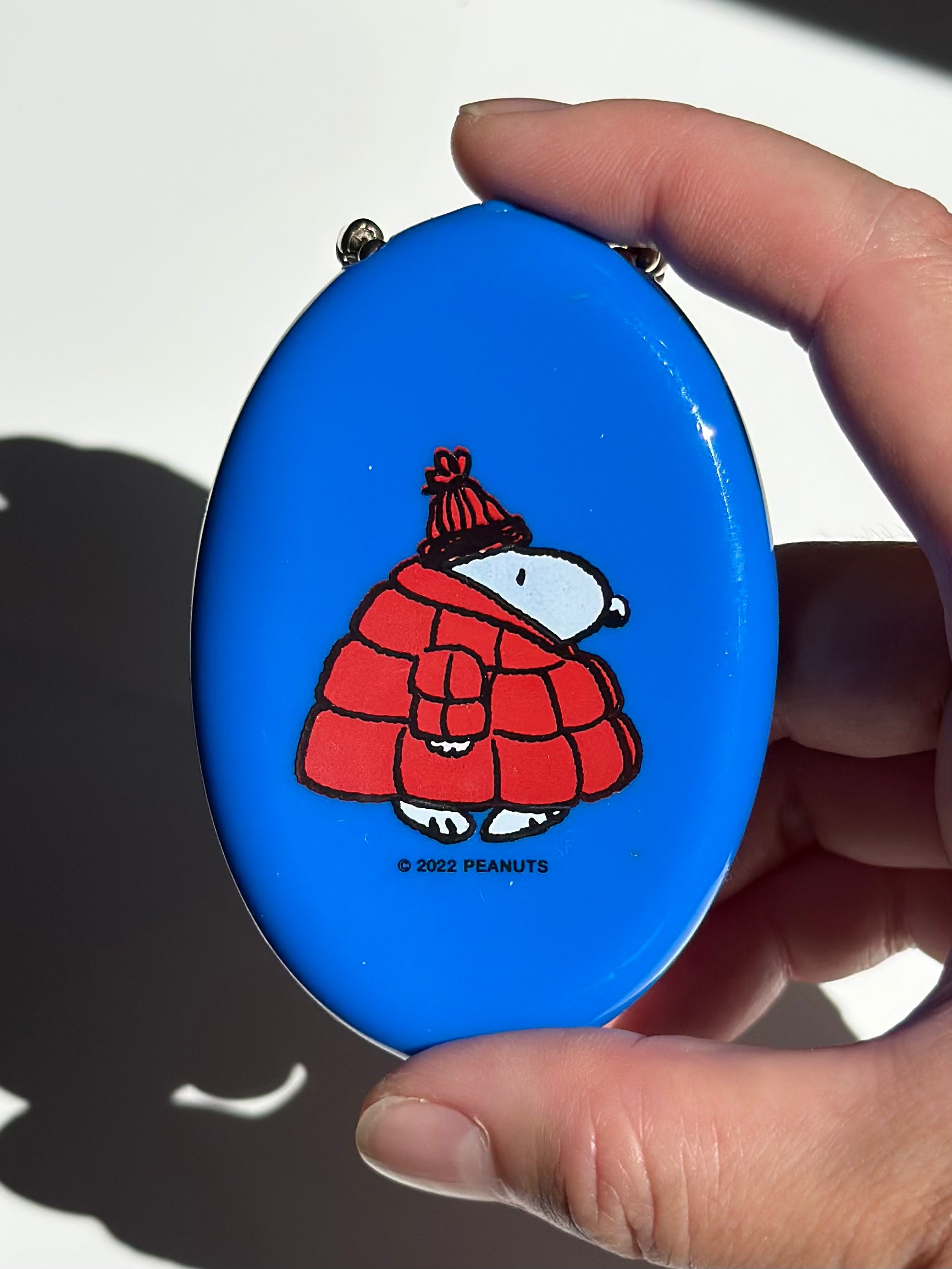 Blue vinyl coin pouch keychain featuring Snoopy in a red puffy coat with knit hat.