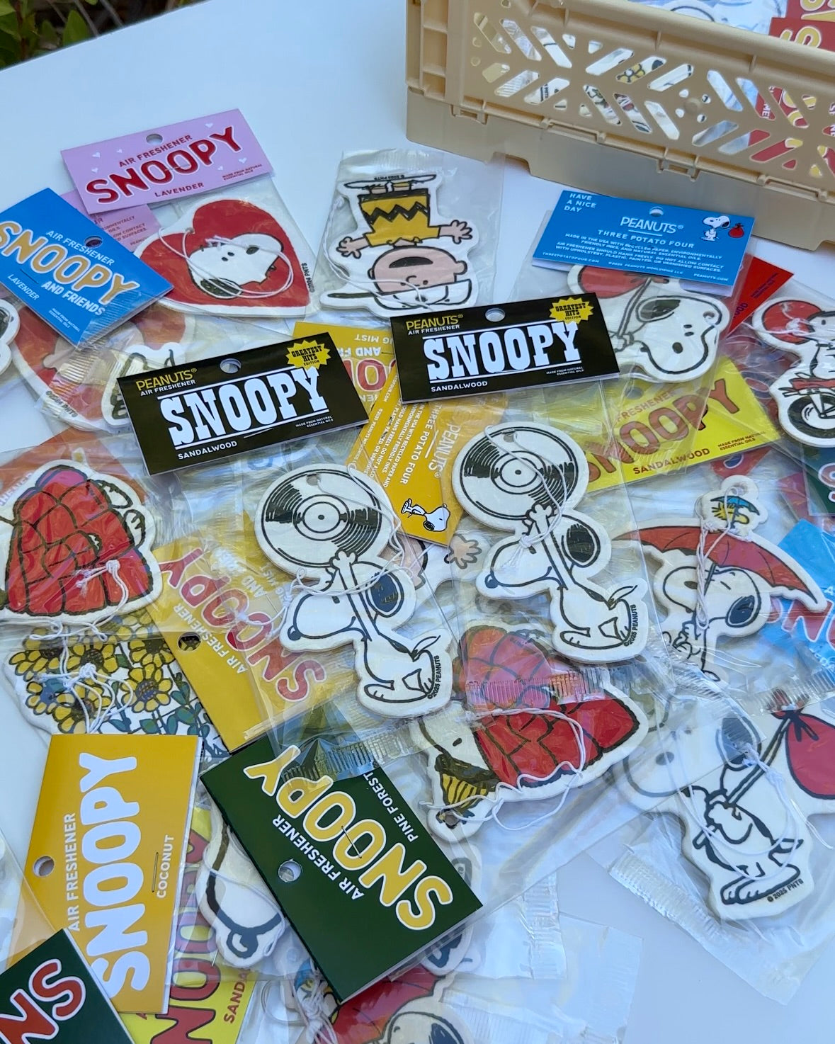 Flat lay of multiple Snoopy Peanuts® air fresheners in assorted designs, with the Snoopy “Greatest Hits” record player sandalwood-scented air freshener featured in the center.