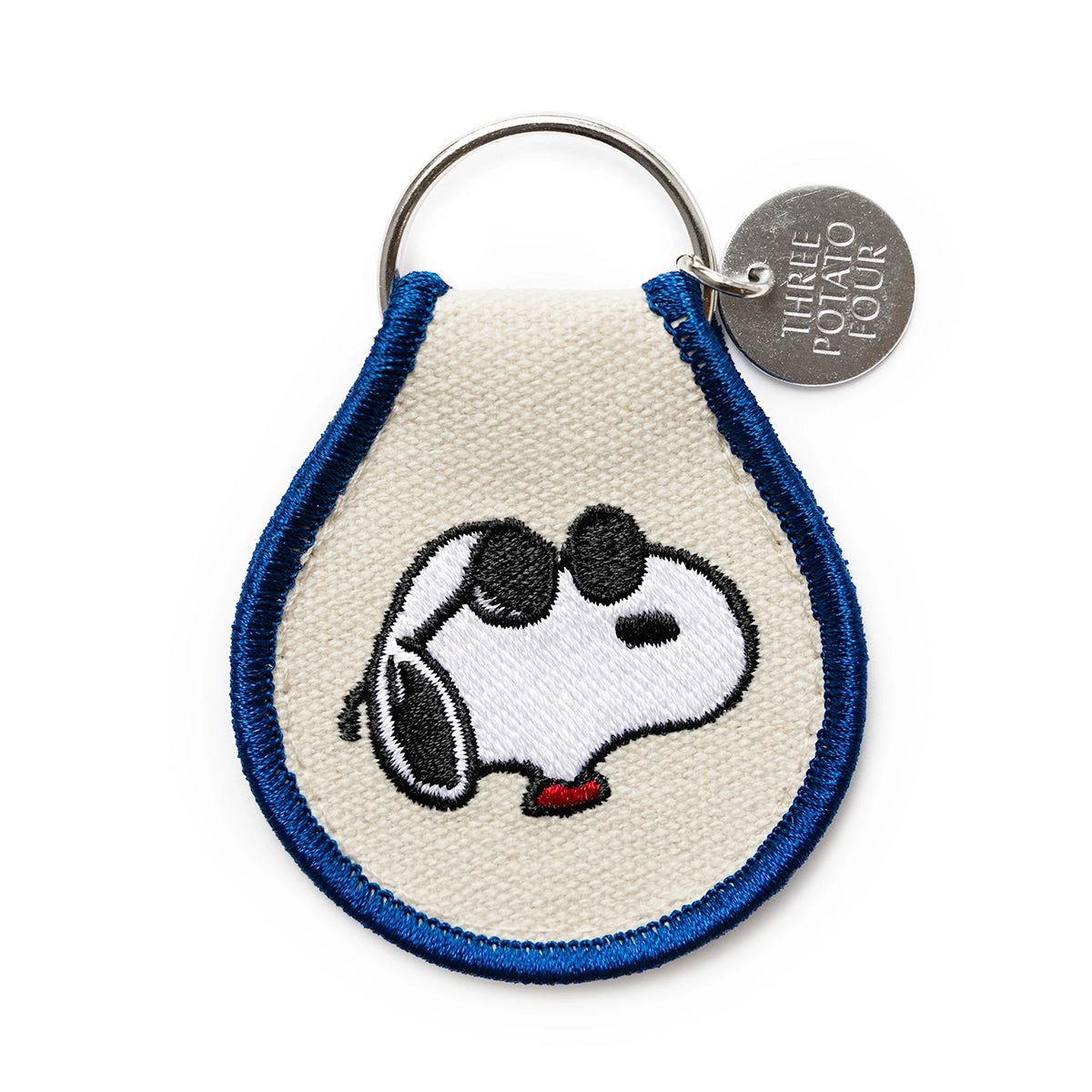 Embroidered Snoopy keychain with bold blue edging, showing Snoopy wearing sunglasses and a red collar. Includes metal Three Potato Four charm — a fun, laid-back accessory for Peanuts fans and collectors.