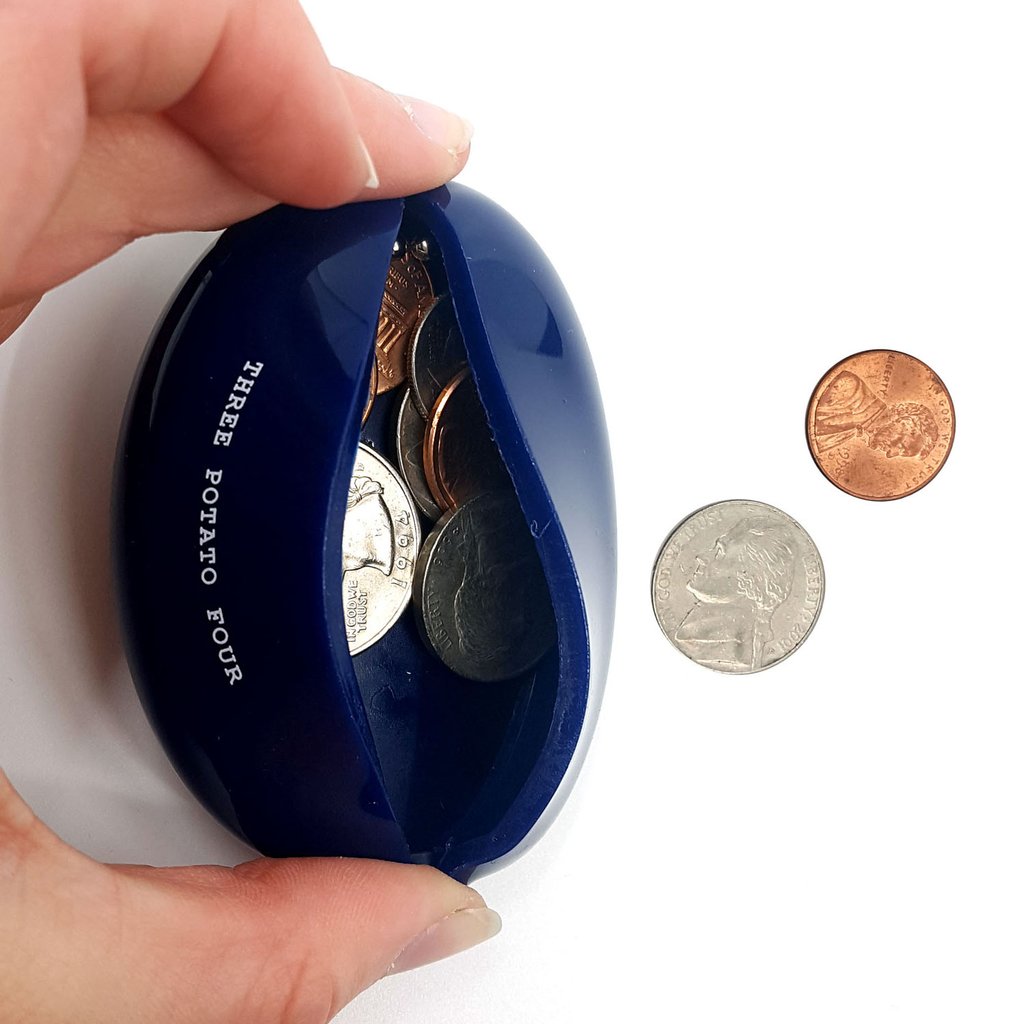 Hand opening a navy blue vintage-style coin pouch filled with loose change. Features the text “Three Potato Four” and flexible slit opening — a nostalgic and functional everyday accessory.