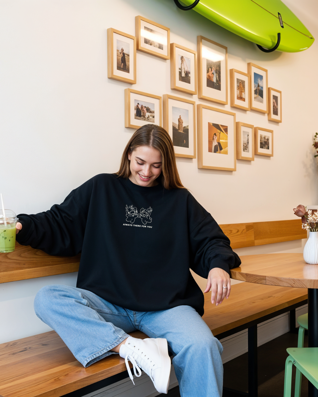 Woman wearing a black oversized embroidered sweatshirt with the phrase “always there for you” while sitting casually indoors