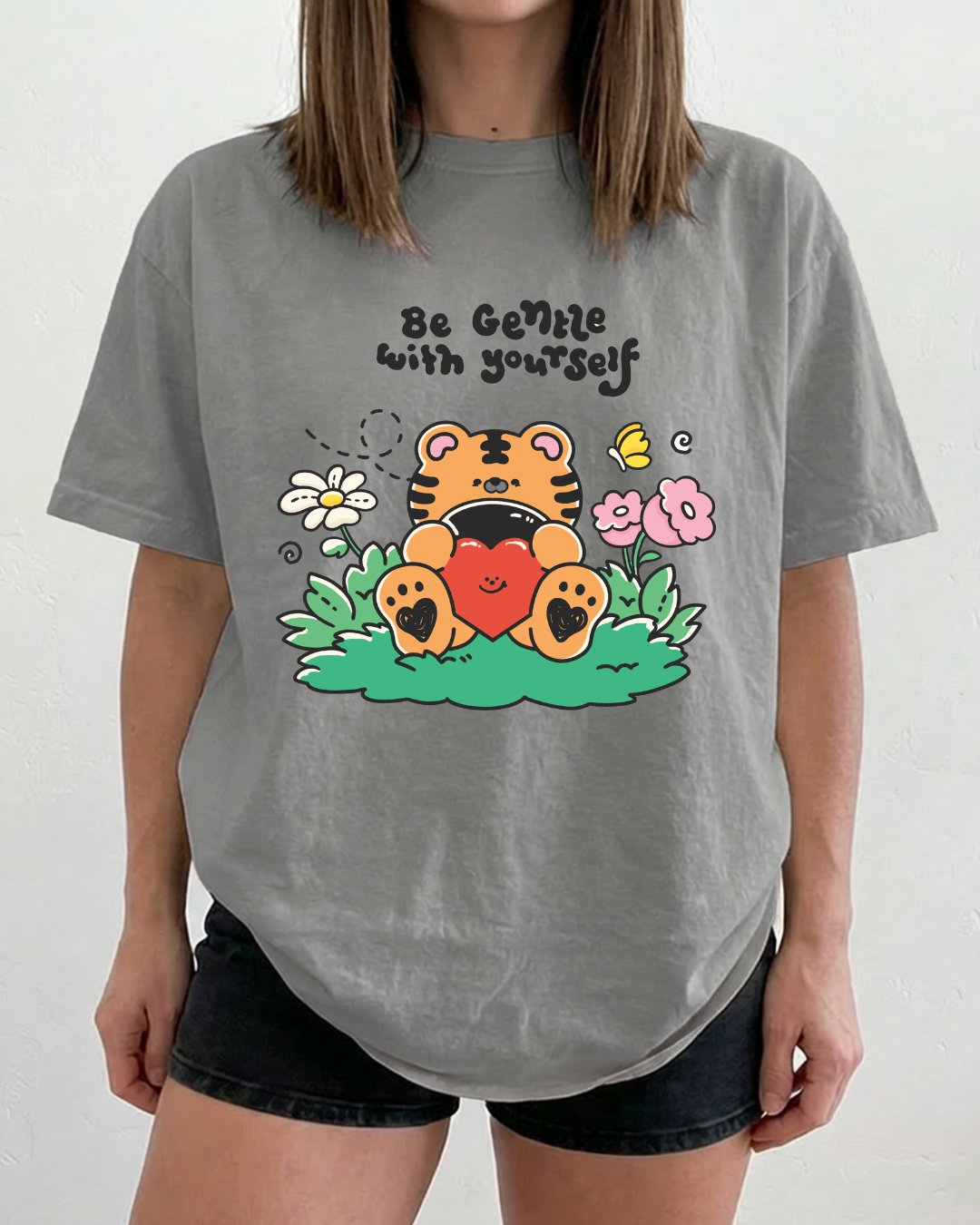 Charcoal gray graphic t-shirt featuring a tiger hugging a heart with the words “be gentle with yourself” on the front