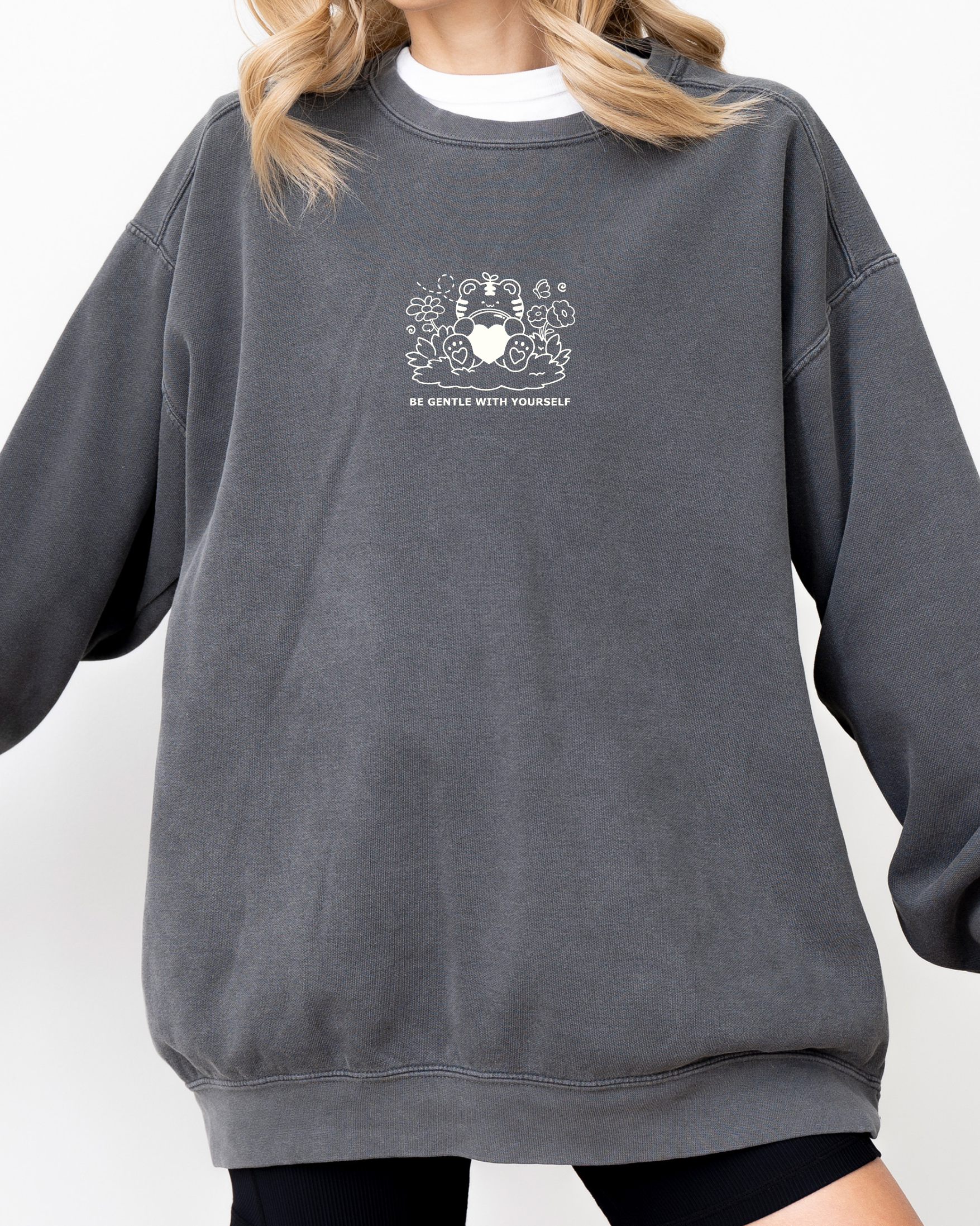 Model wearing an oversized charcoal gray embroidered crewneck sweatshirt with a subtle “Be Gentle With Yourself” design, showing relaxed unisex fit.