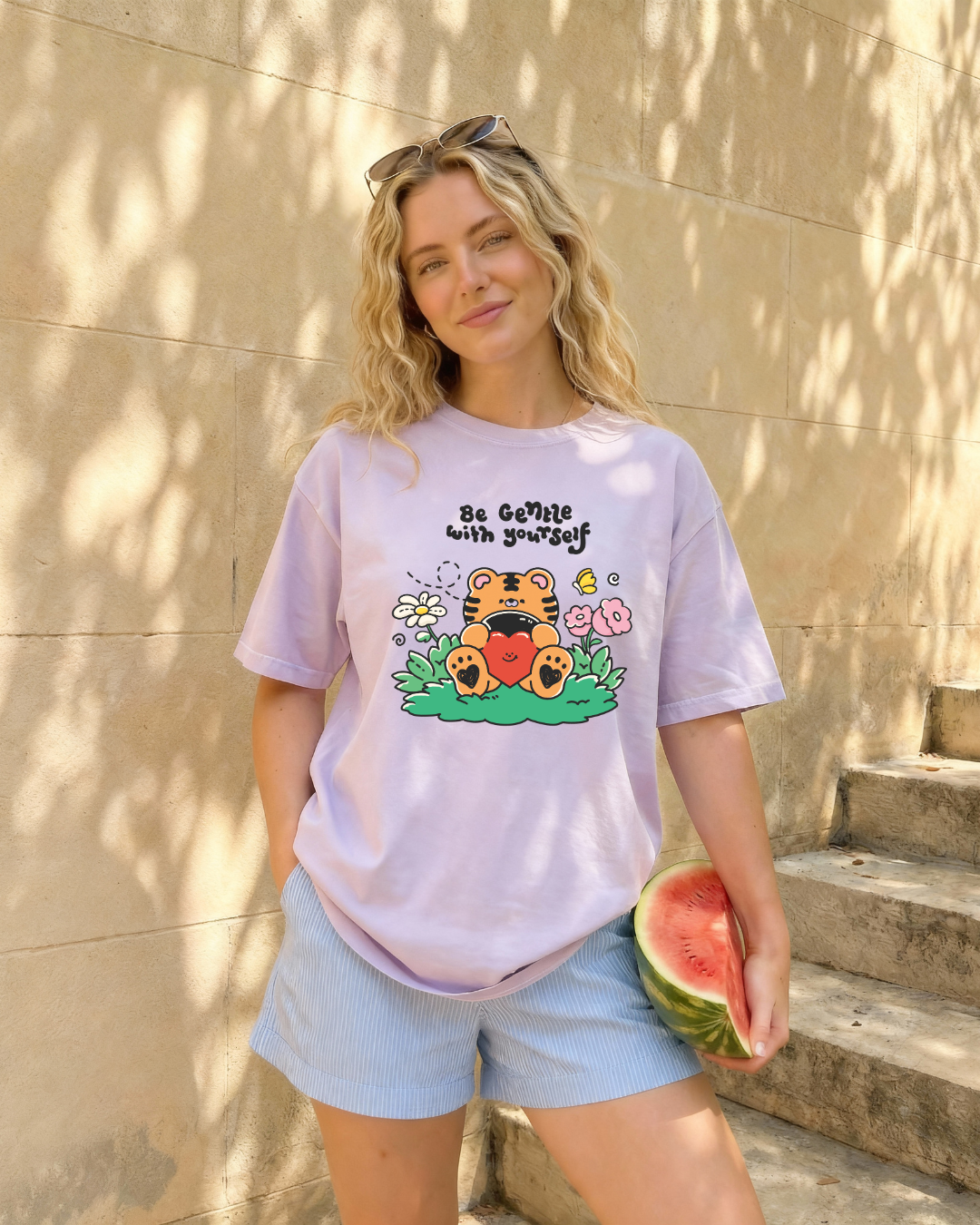 Person wearing a pastel purple “be gentle with yourself” graphic t-shirt styled casually outdoors