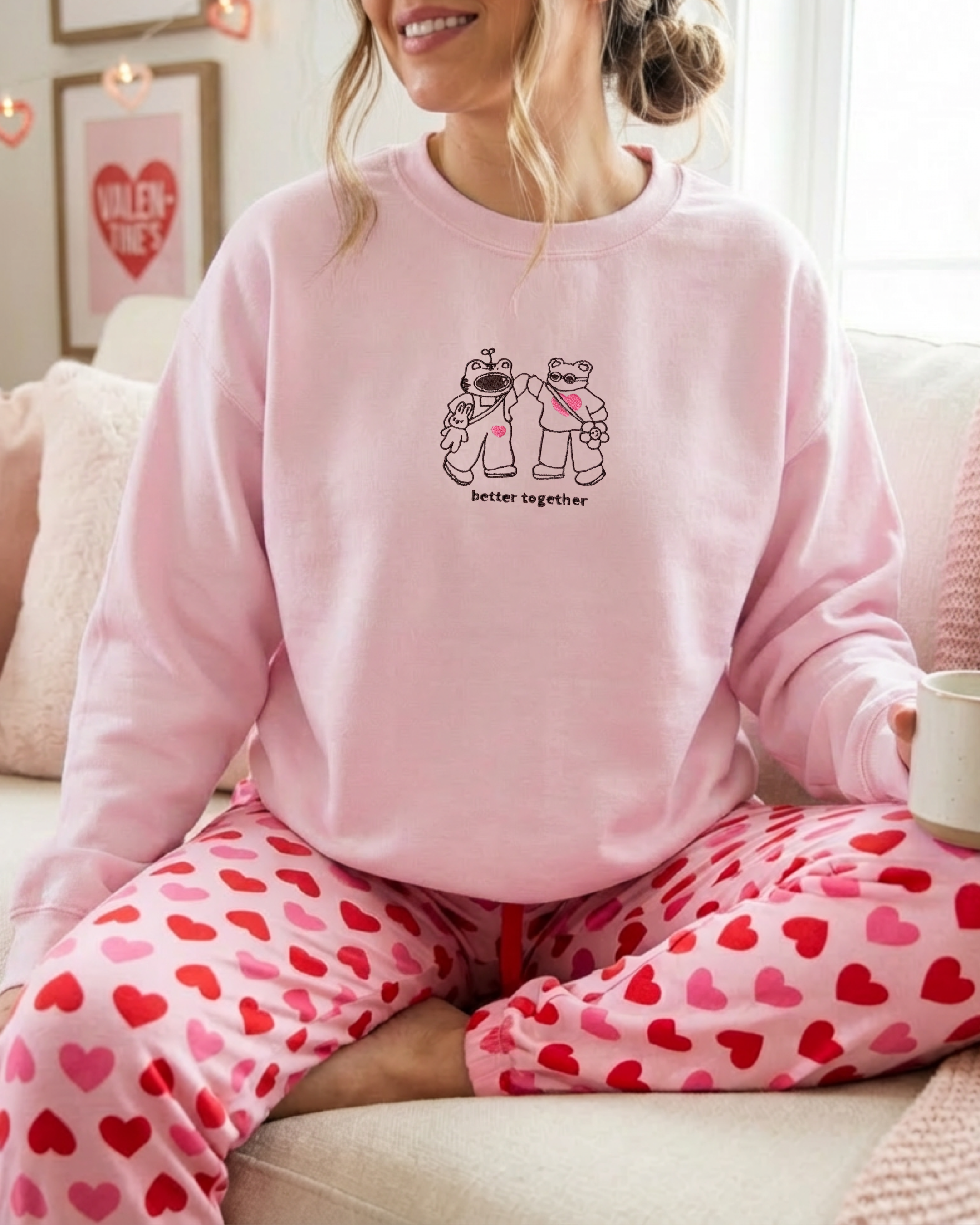Person wearing a pink “Better Together” embroidered sweatshirt while relaxing at home, styled for cozy everyday comfort.