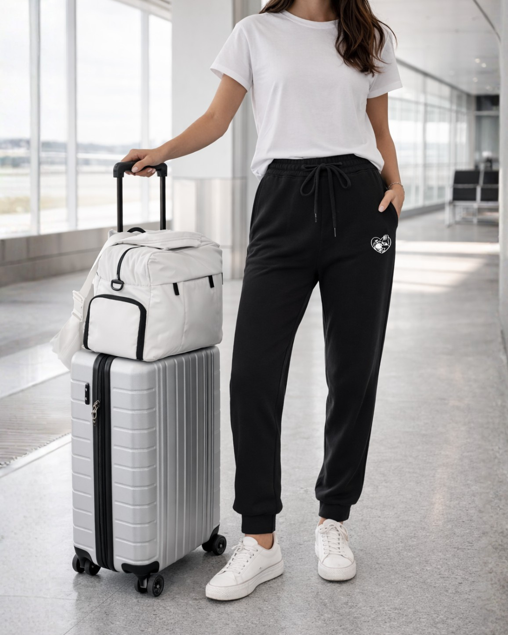 Front view of black embroidered sweatpants for women styled with white t-shirt and sneakers, relaxed fit fleece joggers.
