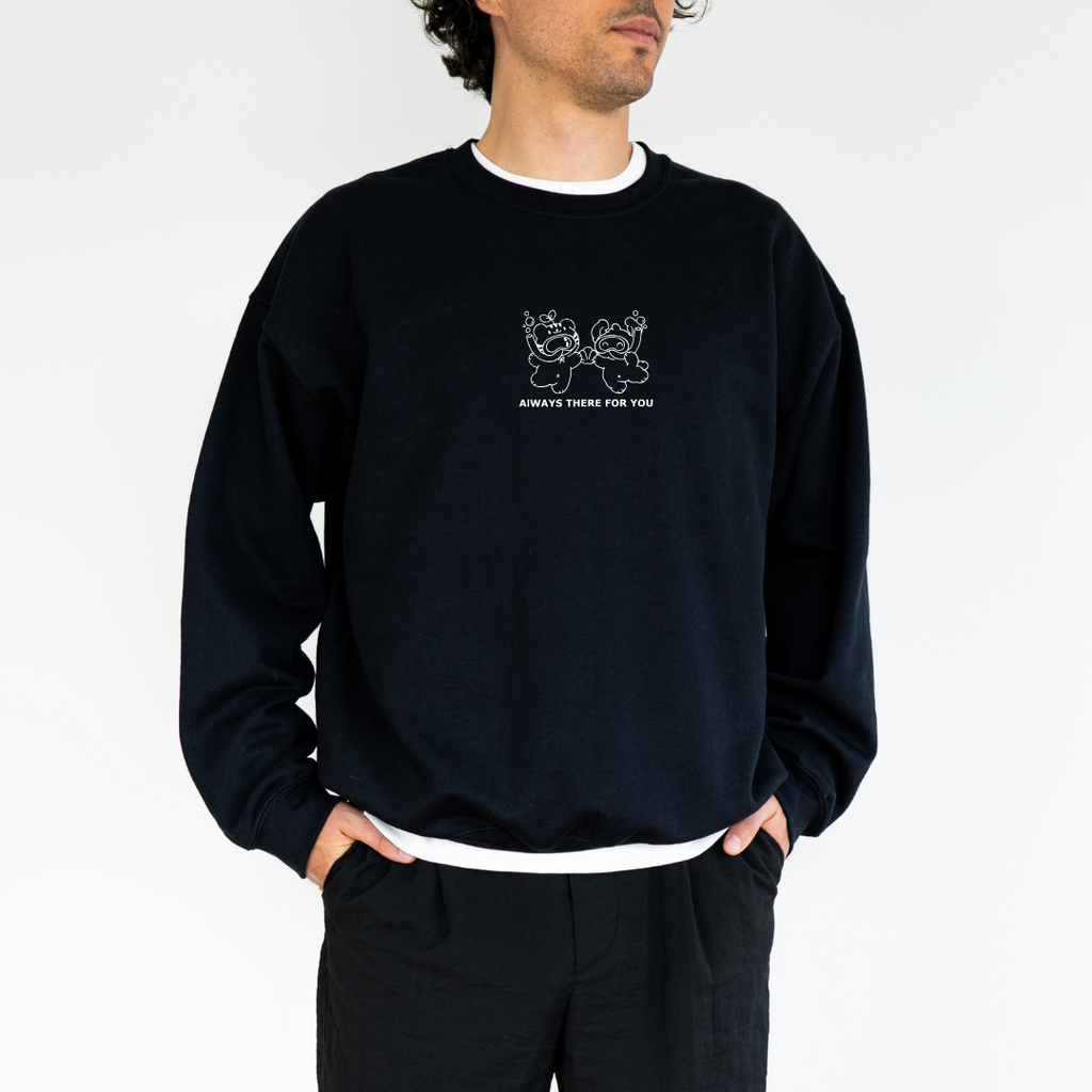 Male model wearing a black crewneck sweatshirt featuring a white embroidered design of two bears holding hands with the text 'Always There For You'. Paired with casual black pants.