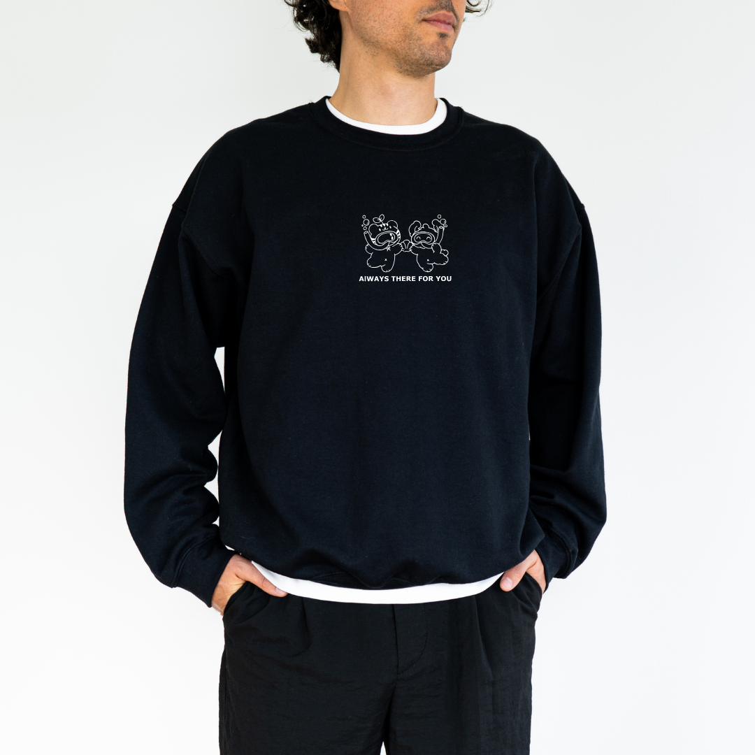 Male model wearing a black crewneck sweatshirt featuring a white embroidered design of two bears holding hands with the text 'Always There For You'. Paired with casual black pants.