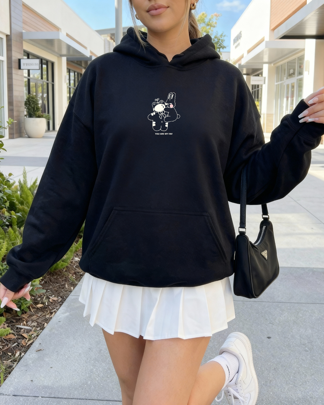 Model wearing a black “You Are My Fav” embroidered hoodie styled as a cozy everyday outfit while walking outdoors