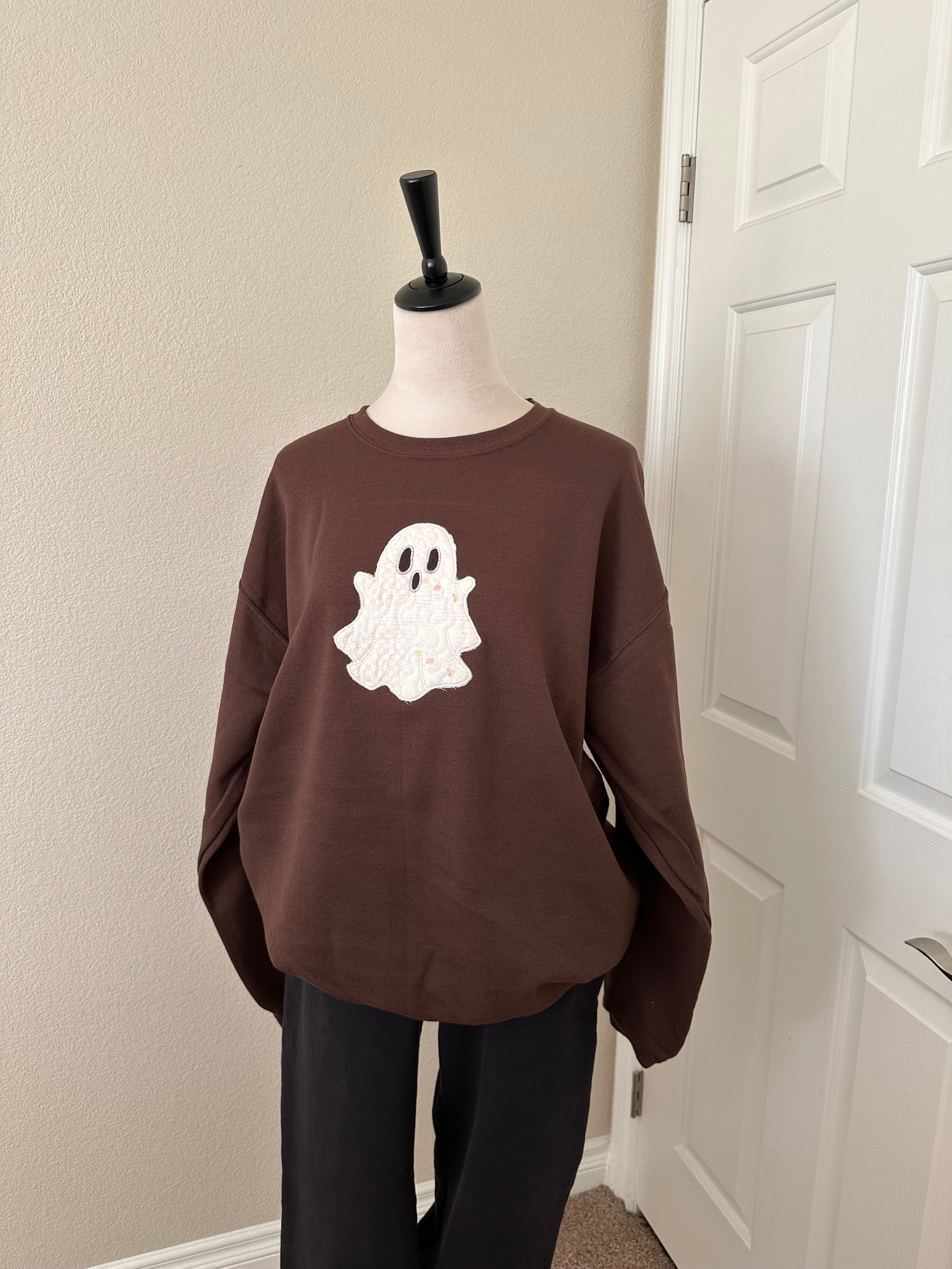 Full brown sweatshirt on mannequin with large white embroidered ghost in the center.