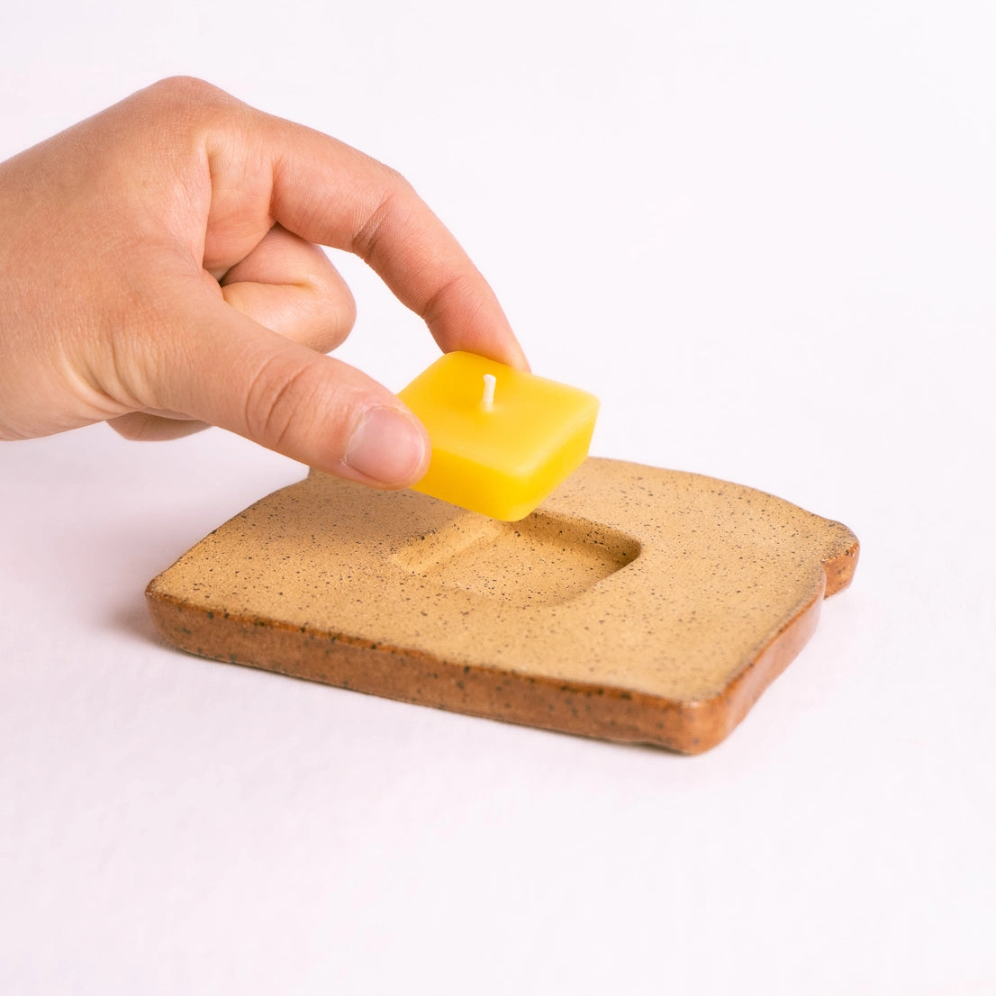 Beeswax butter tealight being placed into ceramic toast holder