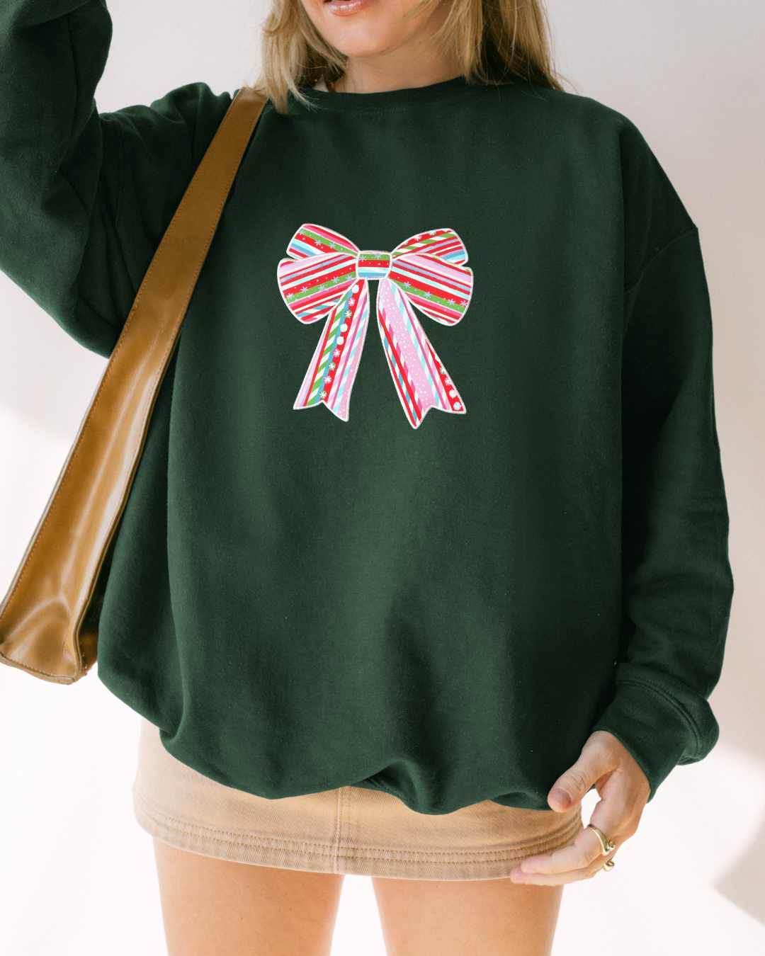 Forest green oversized Christmas sweatshirt featuring an embroidered candy cane striped bow on the front, cozy holiday crewneck for winter outfits and gifting