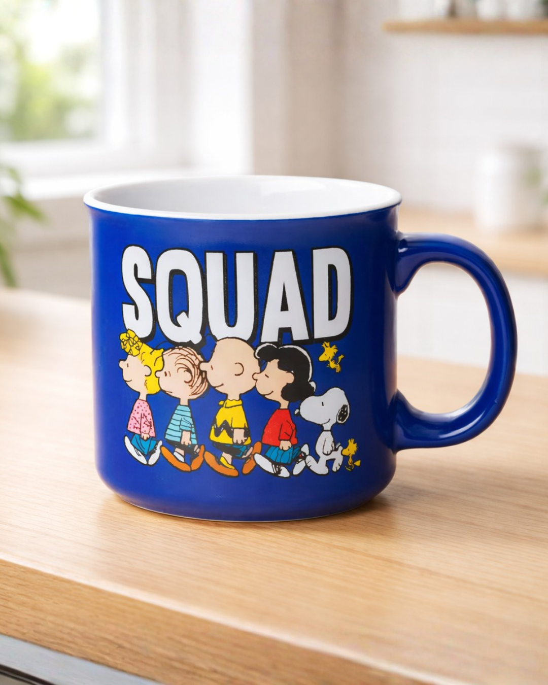 Cartoon Snoopy squad coffee mug with Peanuts characters on blue ceramic mug placed on kitchen counter, novelty mug for coffee and tea