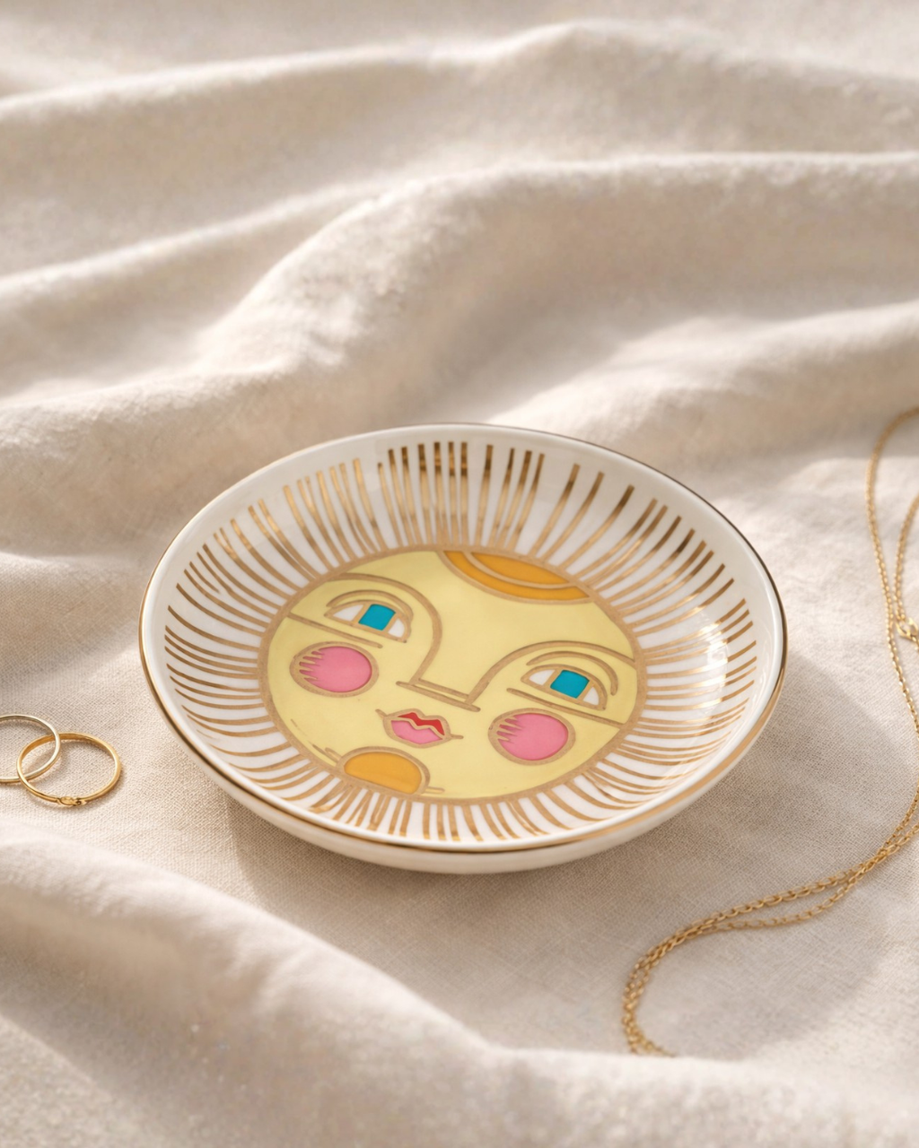 Celestial sun face jewelry dish on soft linen fabric with gold rings and necklace, decorative trinket tray for rings earrings and small jewelry