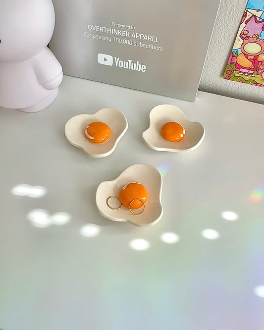 Handmade ceramic egg dish with yolk-shaped bump holding two rings