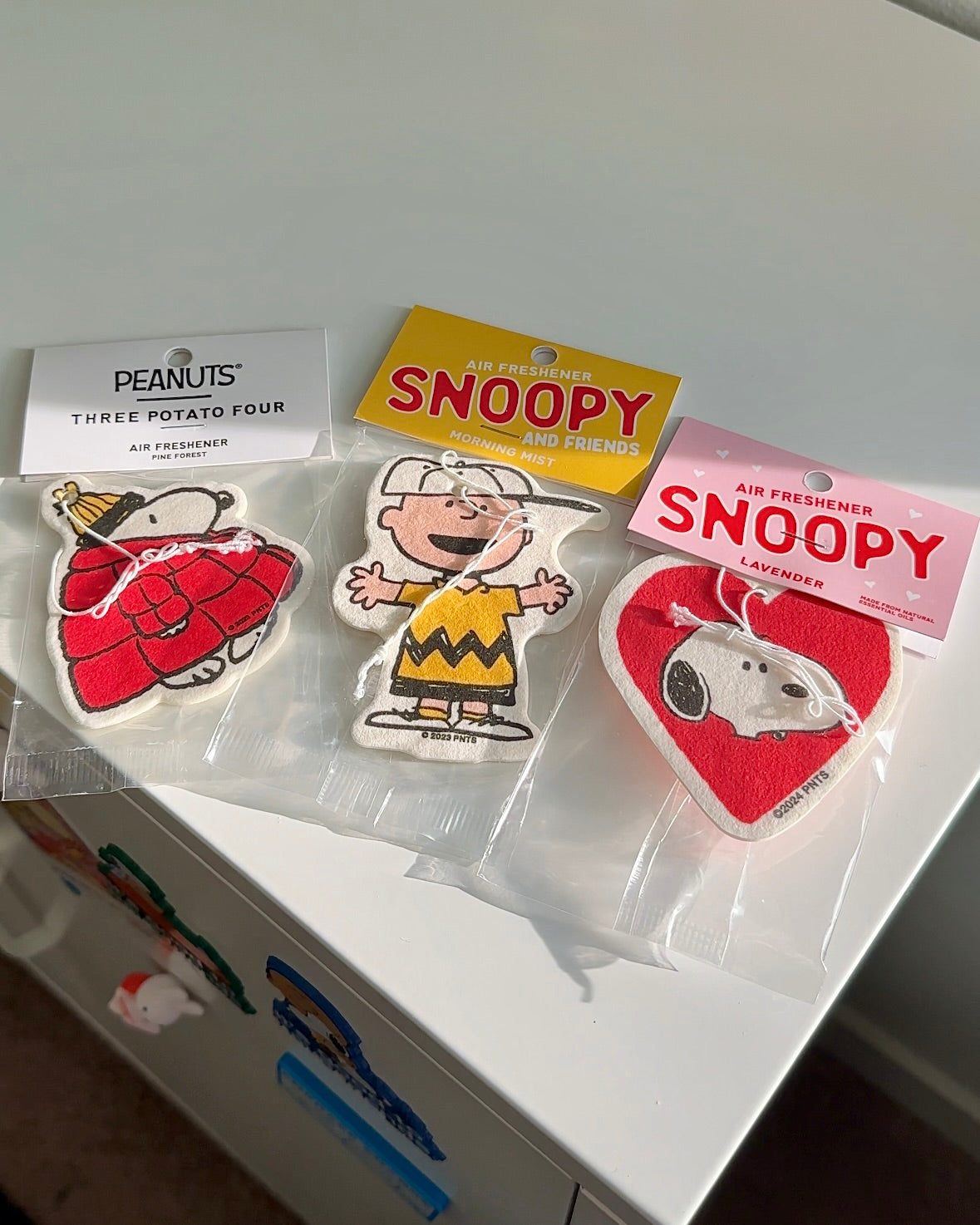 Charlie Brown Morning Mist air freshener shown with other Peanuts designs. Cute scented car accessories for nostalgic and soft-hearted fans.