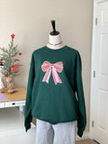 Full view of green sweatshirt with festive bow in natural light