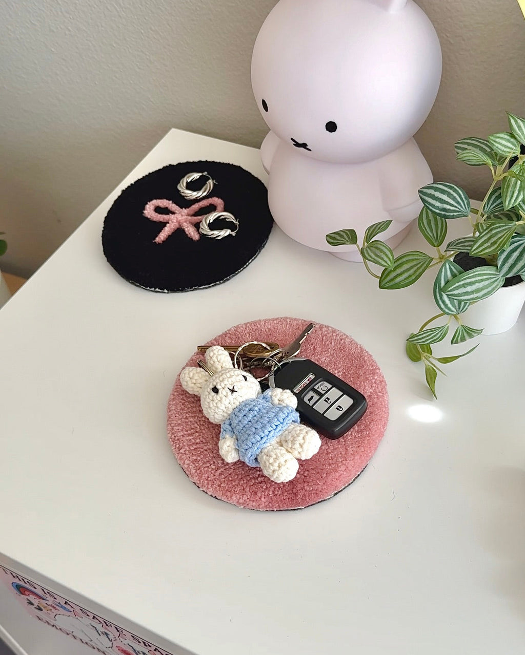 Pink and black bow coasters used as key + jewelry trays on white surface