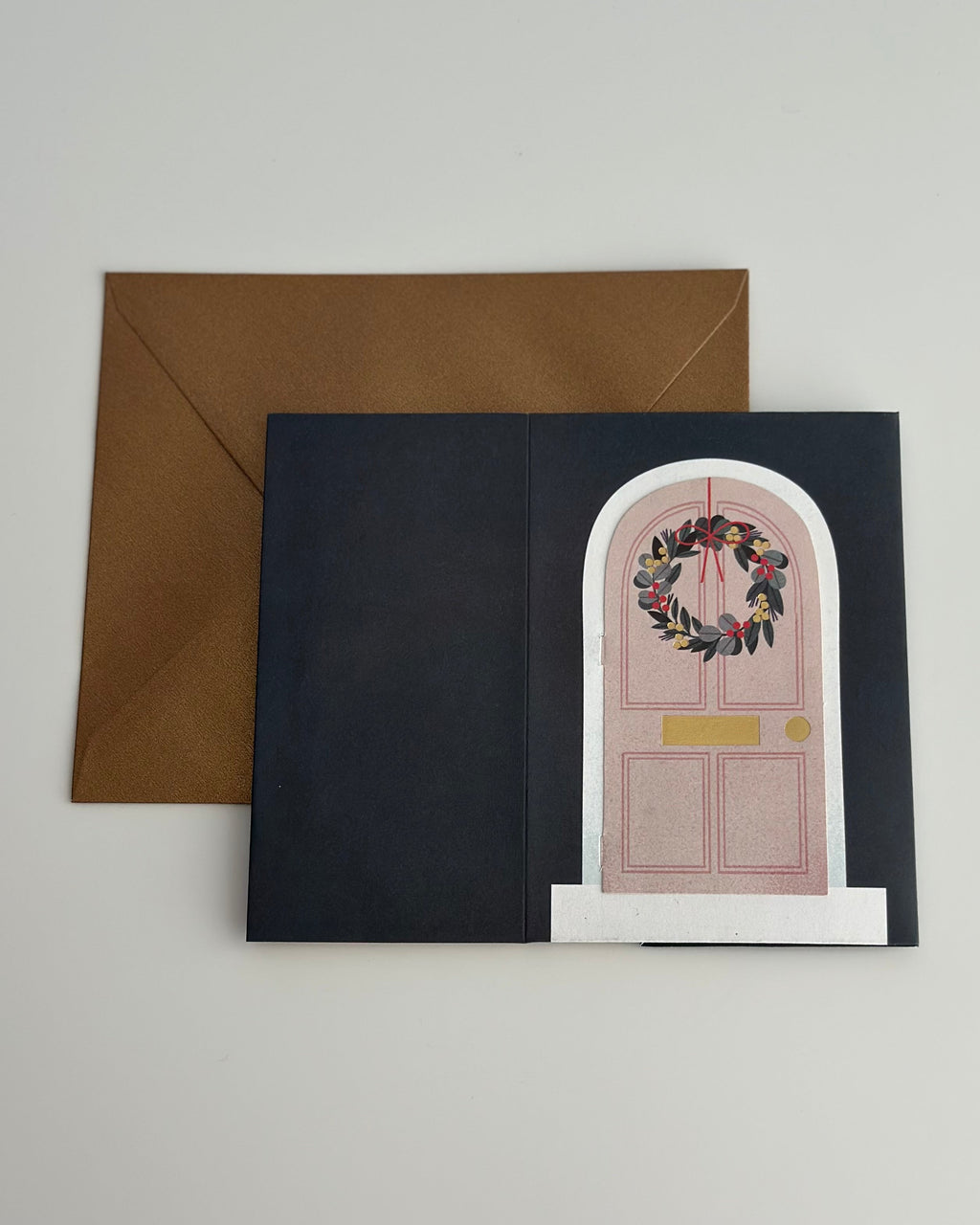 Closed Christmas door card with wreath and metallic gold envelope.