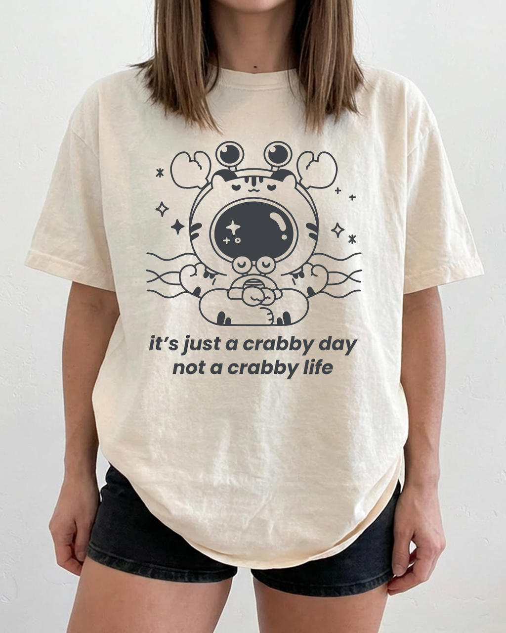 Ivory graphic t-shirt featuring a calm cartoon crab and the phrase “it’s just a crabby day not a crabby life”