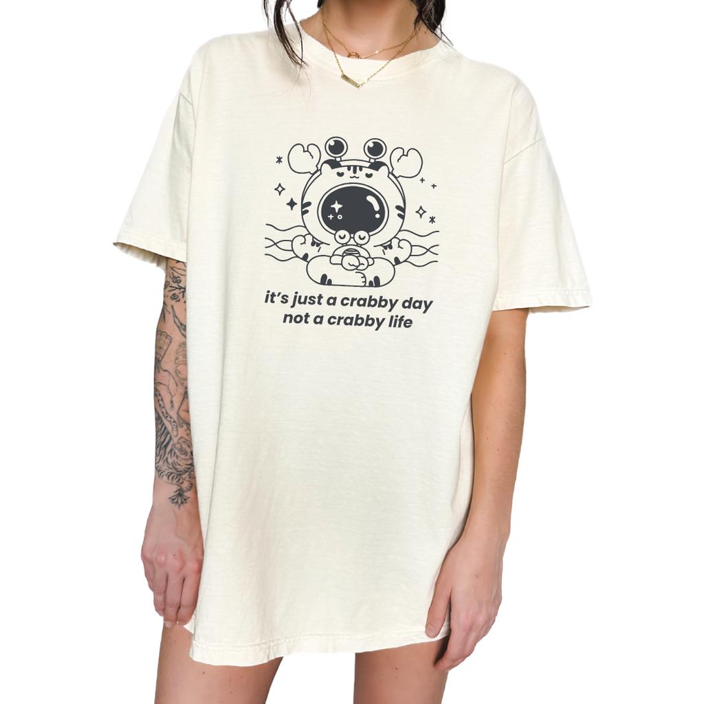 Unisex relaxed fit ivory t-shirt featuring a minimalist crab graphic and the phrase “it’s just a crabby day not a crabby life,” a supportive mental health shirt