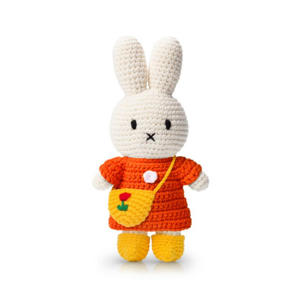 Crochet bunny doll wearing an orange dress, yellow booties, and a tiny tulip-embroidered crossbody bag — a charming handmade plush full of cozy detail.