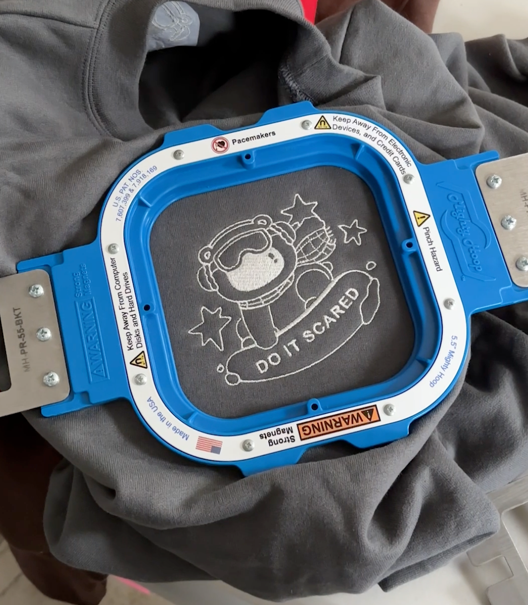 Charcoal gray oversized crewneck sweatshirt with subtle “Do It Scared” polar bear embroidery, laid flat to show relaxed fit and minimal motivational design.