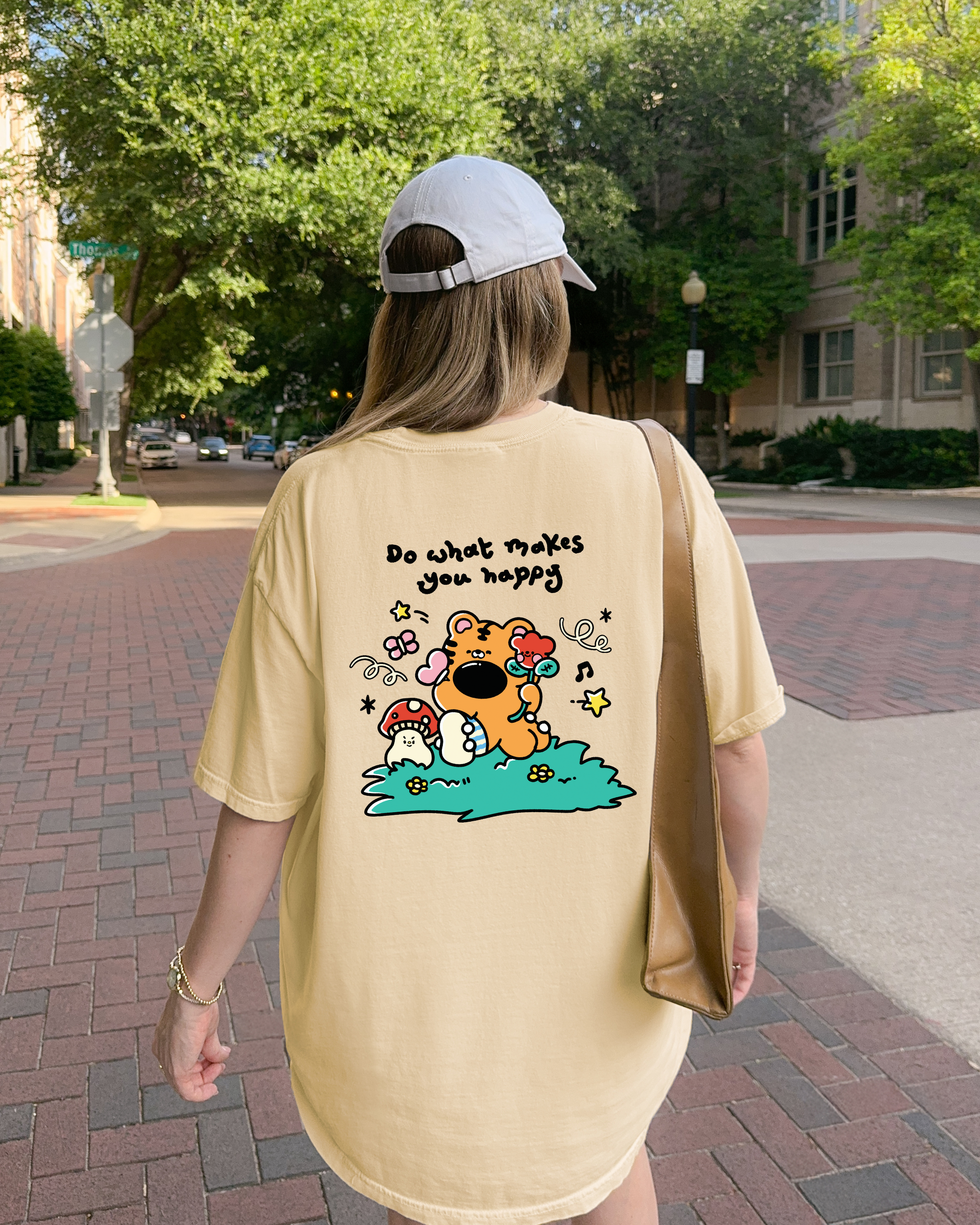 Butter yellow graphic t shirt with cute illustrated back print and the phrase do what makes you happy worn casually outdoors