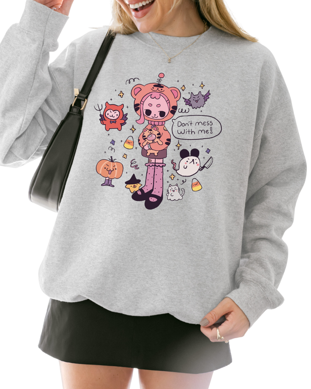 Person wearing an ash gray graphic sweatshirt with a cute illustrated character and the phrase “don’t mess with me”