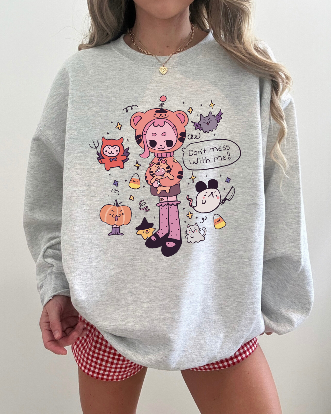 Ash gray crewneck sweatshirt featuring a playful illustrated character surrounded by small icons and a speech bubble reading “don’t mess with me”