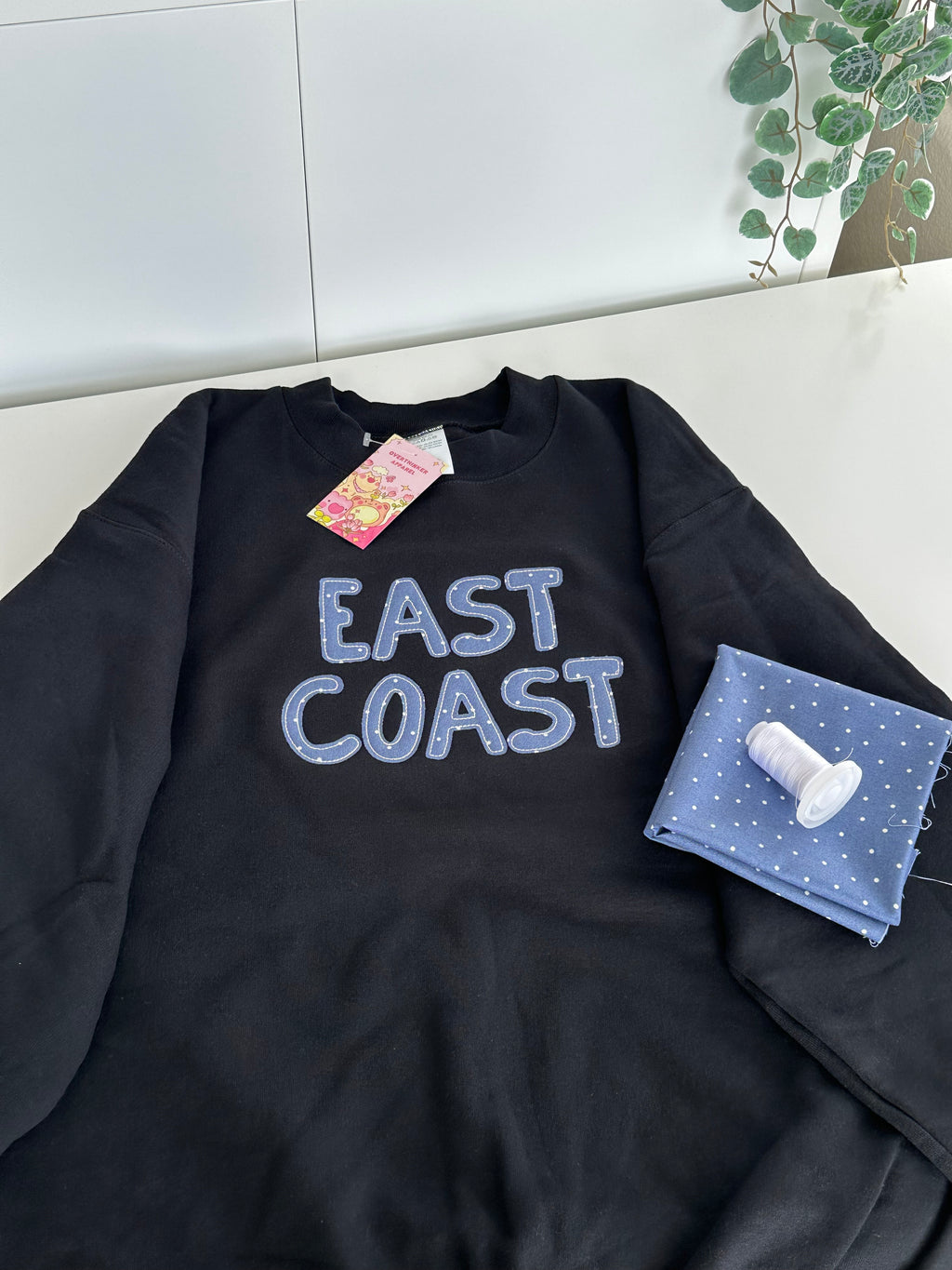black east coast sweatshirt with embroidery detail shown with fabric and thread casual cozy aesthetic