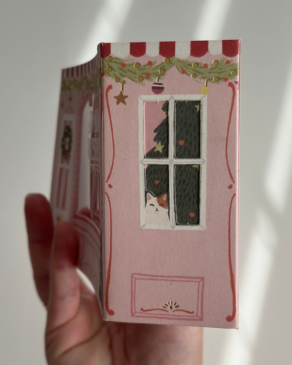 Pop-up bakery holiday card side view with cat in window and Christmas tree.