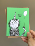 Funny cat birthday card with scruffy hand-drawn cat wearing a polka dot party hat and holding a balloon, saying ‘You’re Old’ on green background with brown kraft envelope.