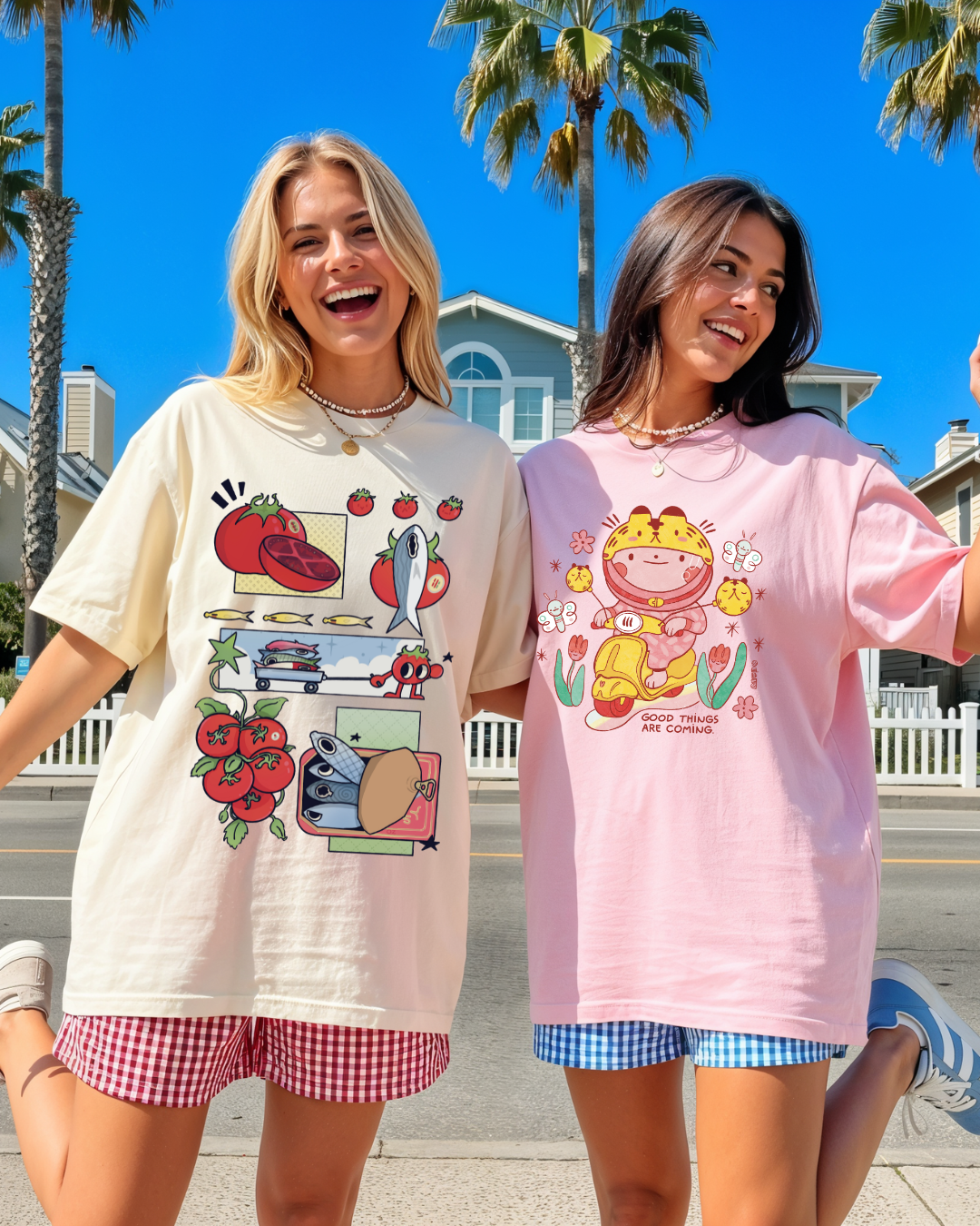 Two women wearing graphic t-shirts outdoors, including a pink tee with a playful illustration and the phrase “good things are coming”