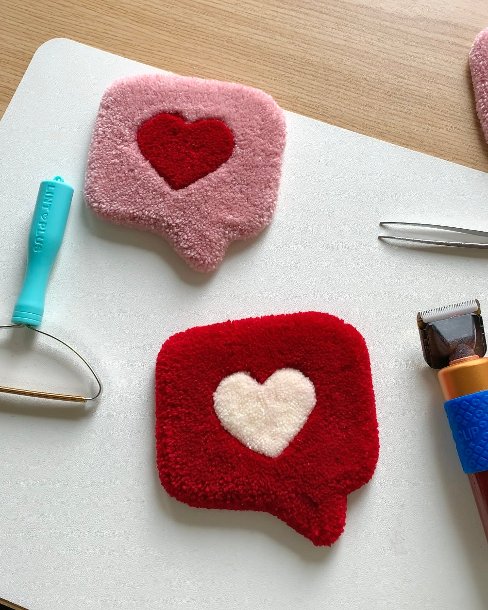 Handmade tufted heart mug rugs in pink and red with plush texture, shown with crafting tools, cozy coaster and jewelry mat for desks or vanities.