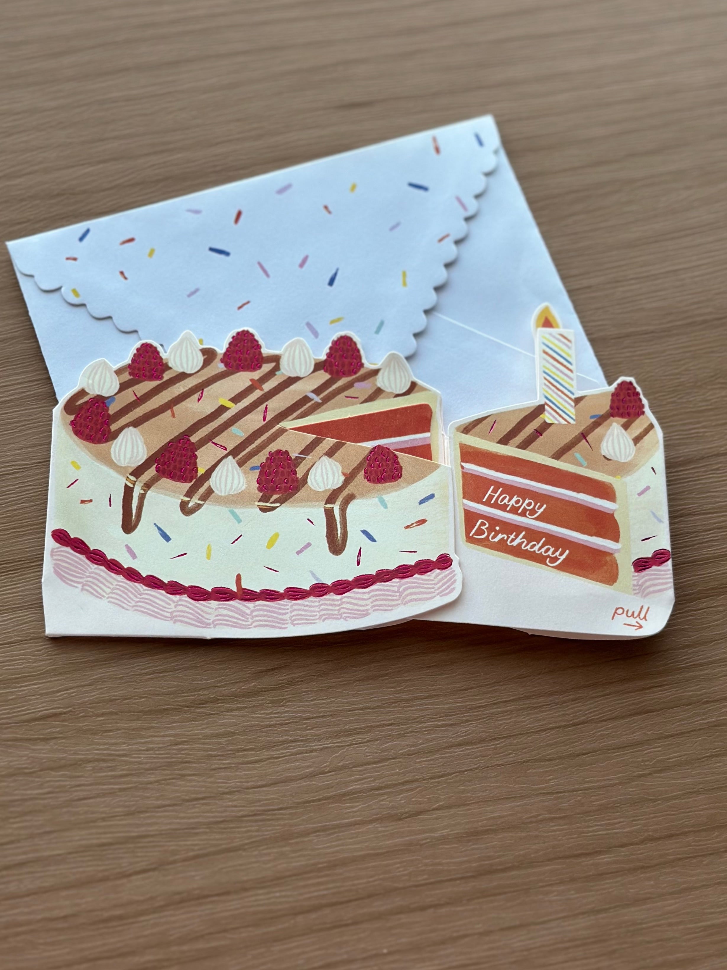 Interactive birthday cake greeting card with pull-tab candle that lights up and reveals “Happy Birthday” message, paired with a sprinkle envelope.