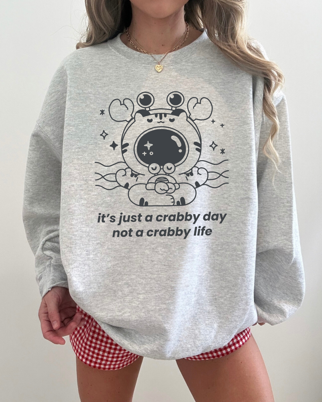 Ash gray crewneck sweatshirt featuring a calm crab illustration and the phrase “it’s just a crabby day, not a crabby life”