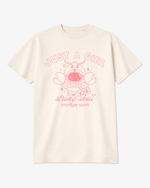 Ivory unisex graphic tee featuring a pink lobster astronaut with the phrase “Just a Girl – Strong Shell, Stronger Spirit,” a soft coastal-inspired shirt for strong women.