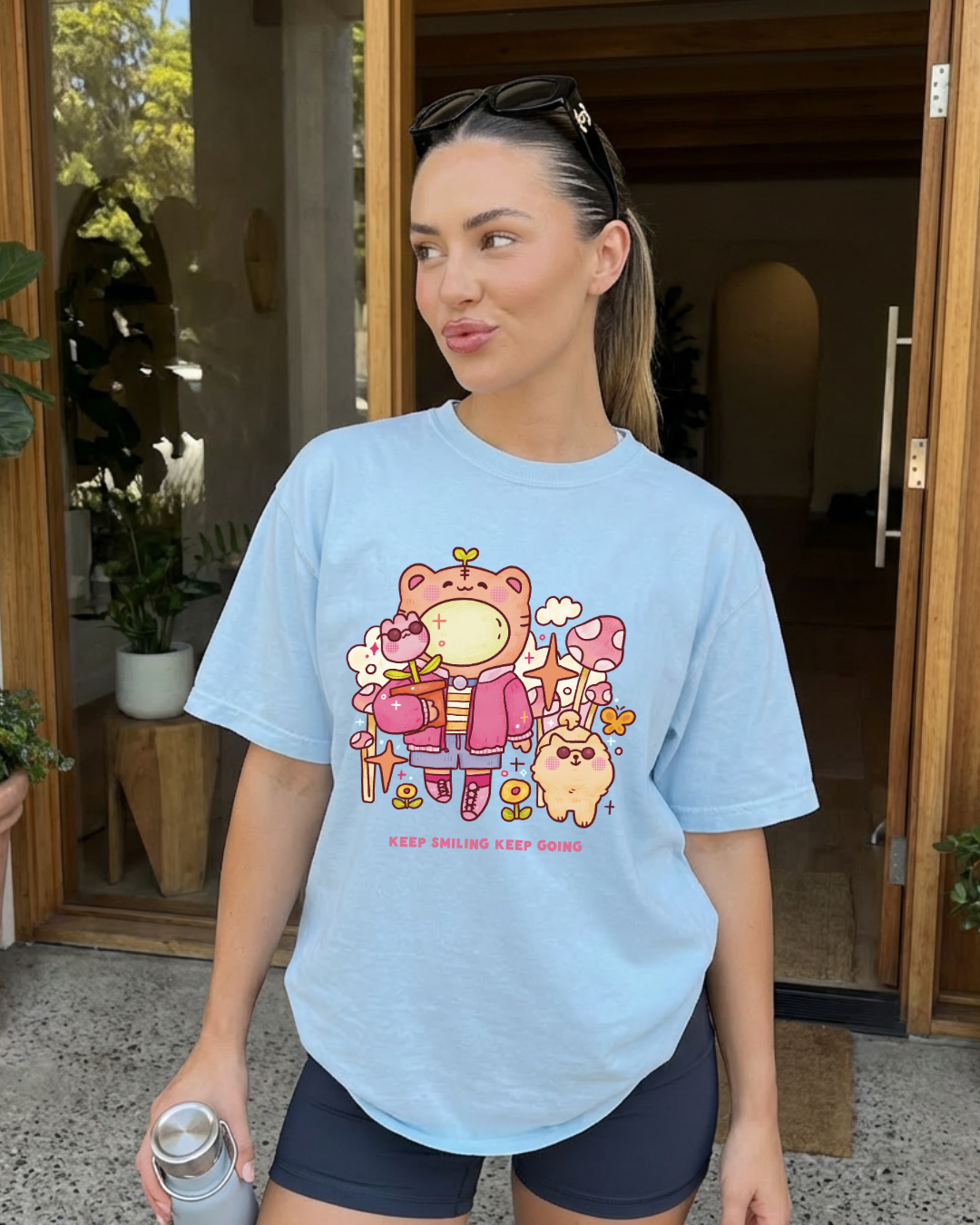 Woman wearing a light blue “keep smiling keep going” graphic tee styled casually for an everyday outfit
