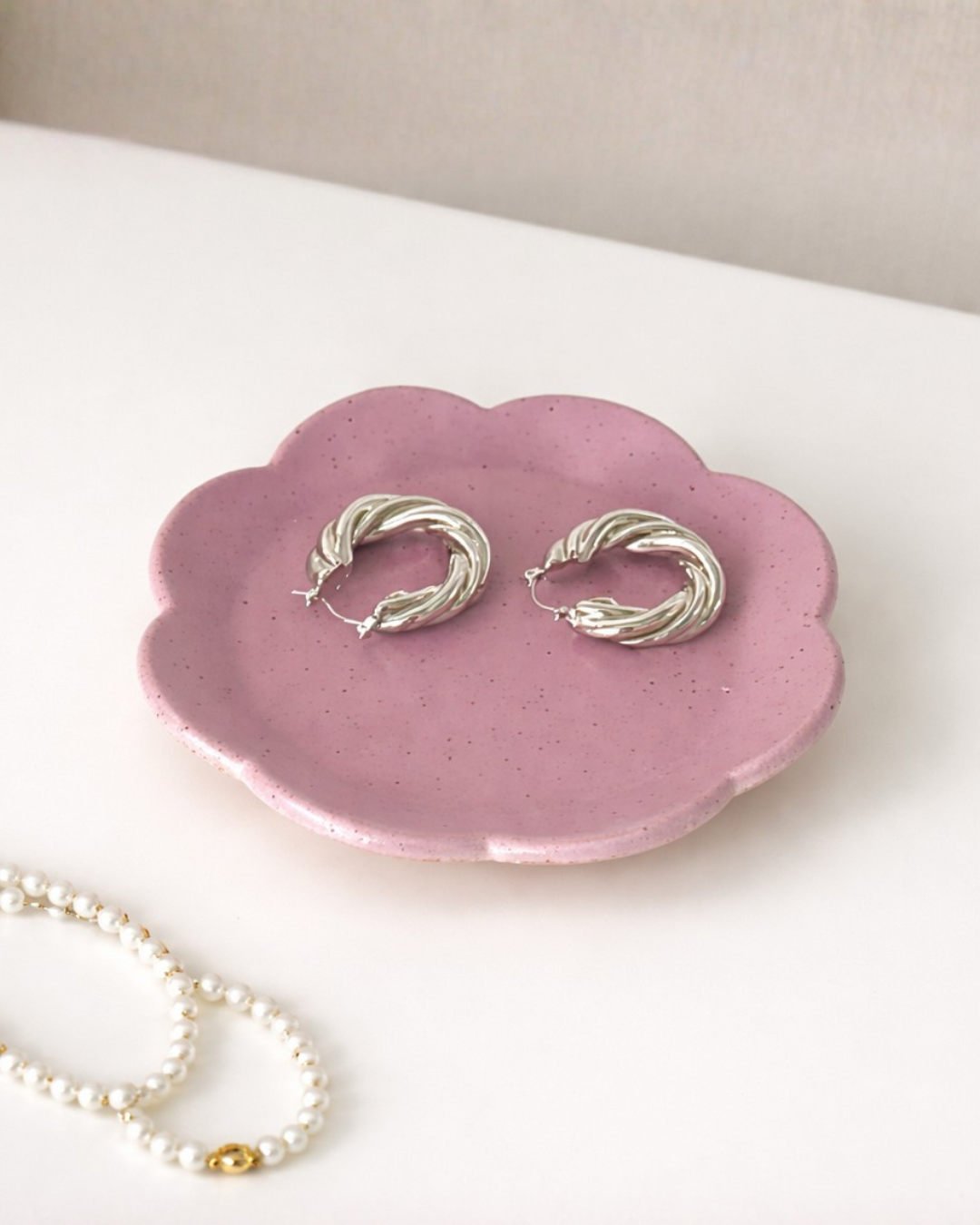Cute purple handmade ceramic flower ring holder dish with gold earrings on minimal white table, jewelry organizer tray for dresser or nightstand
