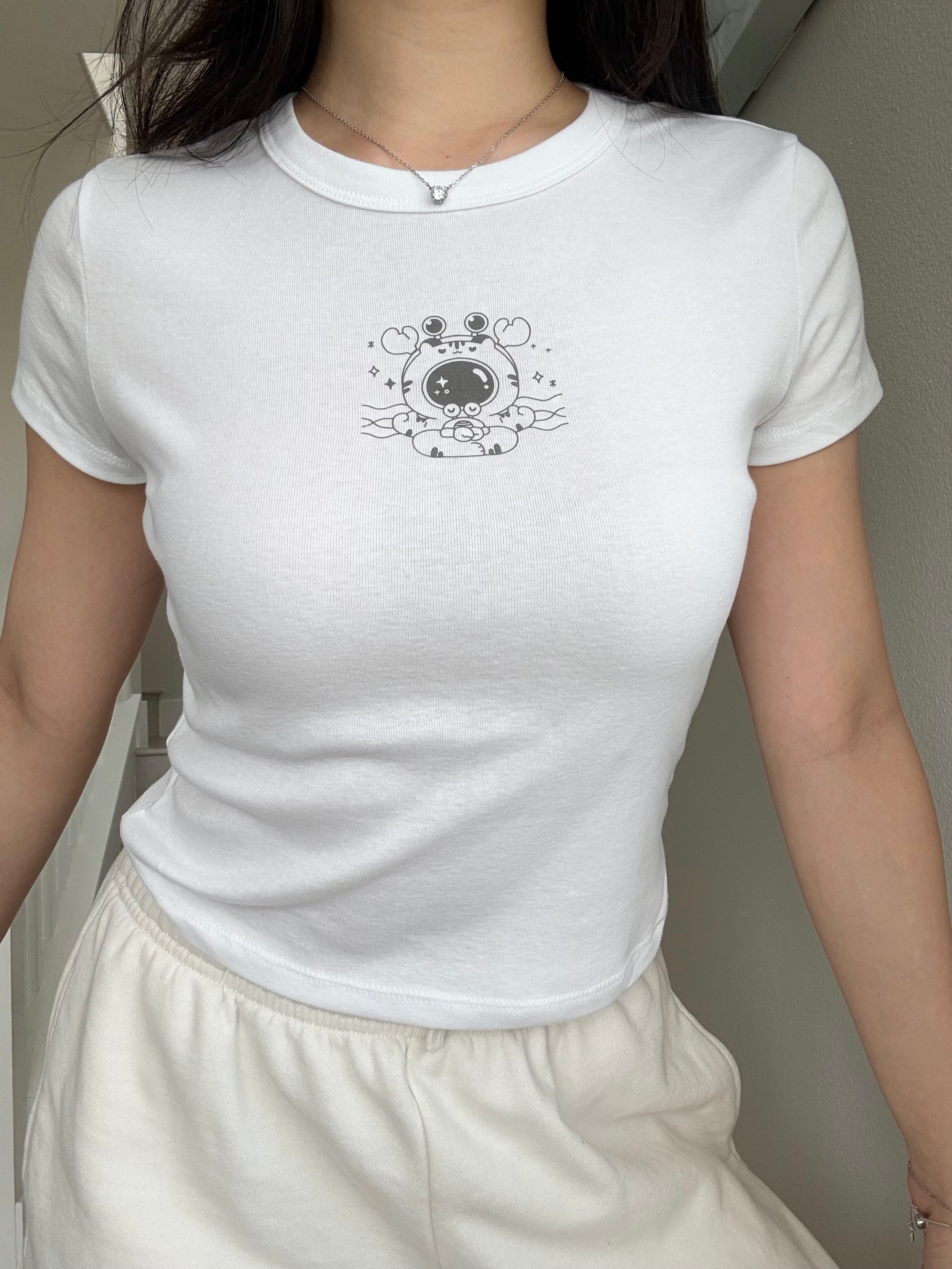 White cropped baby tee featuring a small meditating crab graphic in a minimalist style