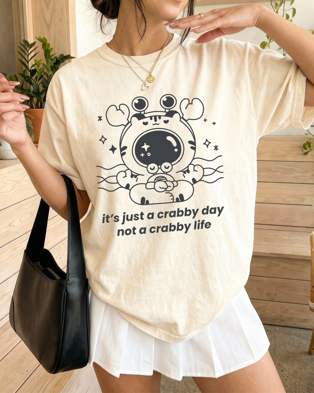 Person wearing an ivory mental health graphic tee with a cute crab illustration and calming message, styled casually for an everyday comforting outfit