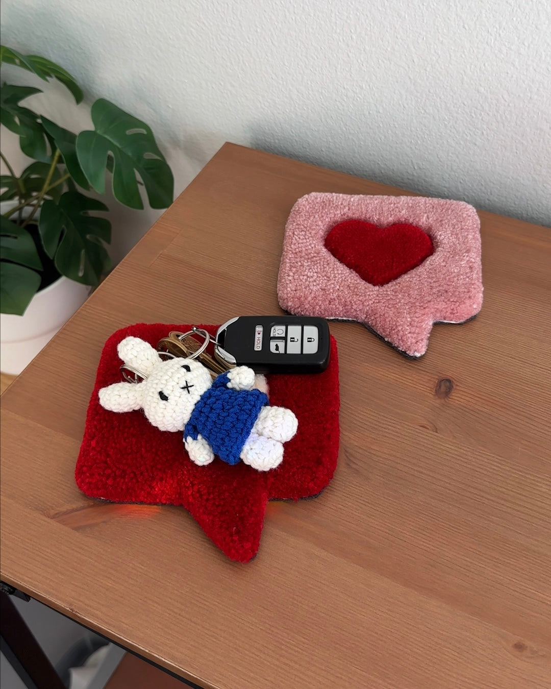 Miffy crochet keychain in a navy blue dress attached to keys and resting on a desk, soft cotton bag charm used as everyday carry.